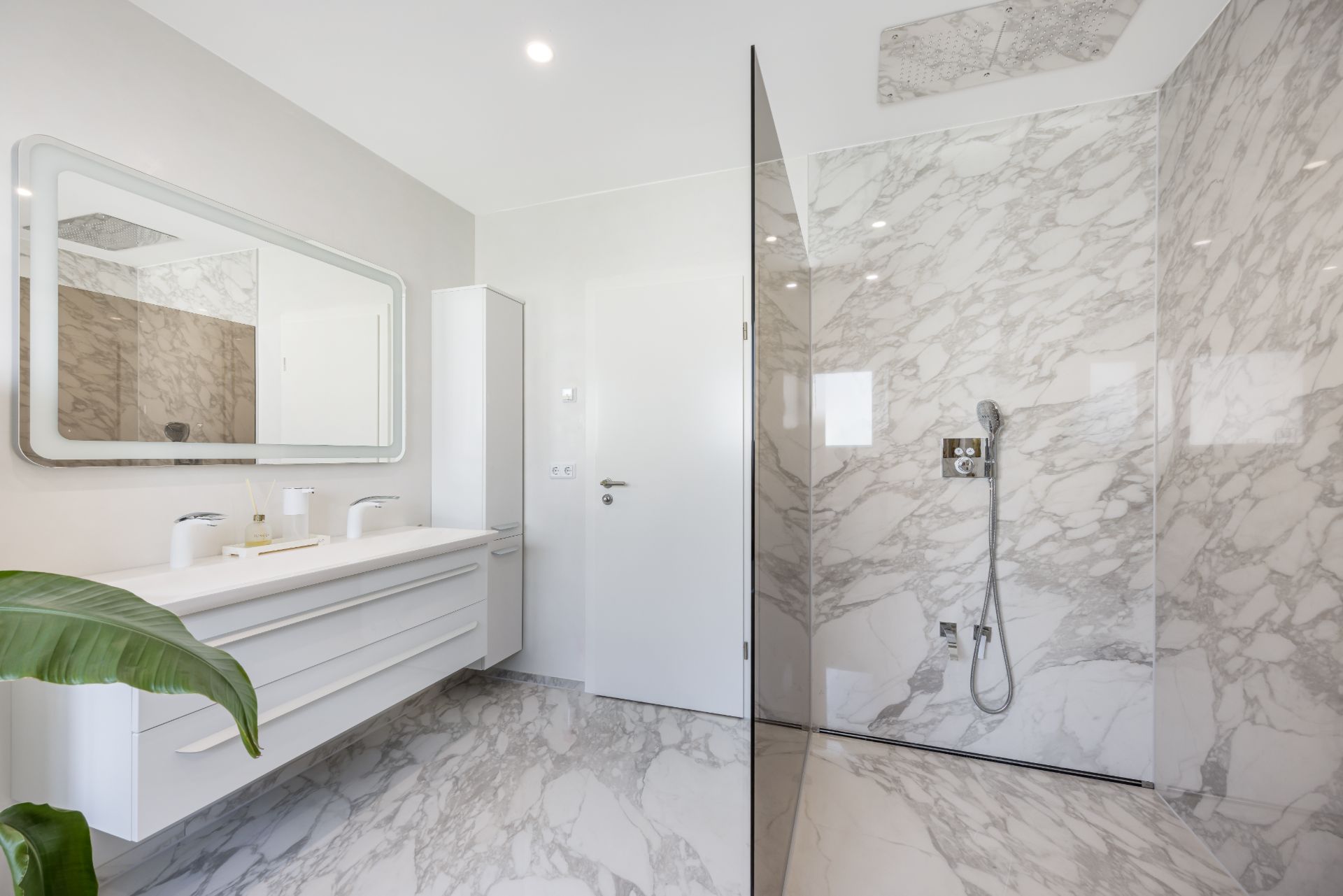 Modernes Badezimmer mit großer Dusche, Marmorwänden, Waschbecken und großem Spiegel.