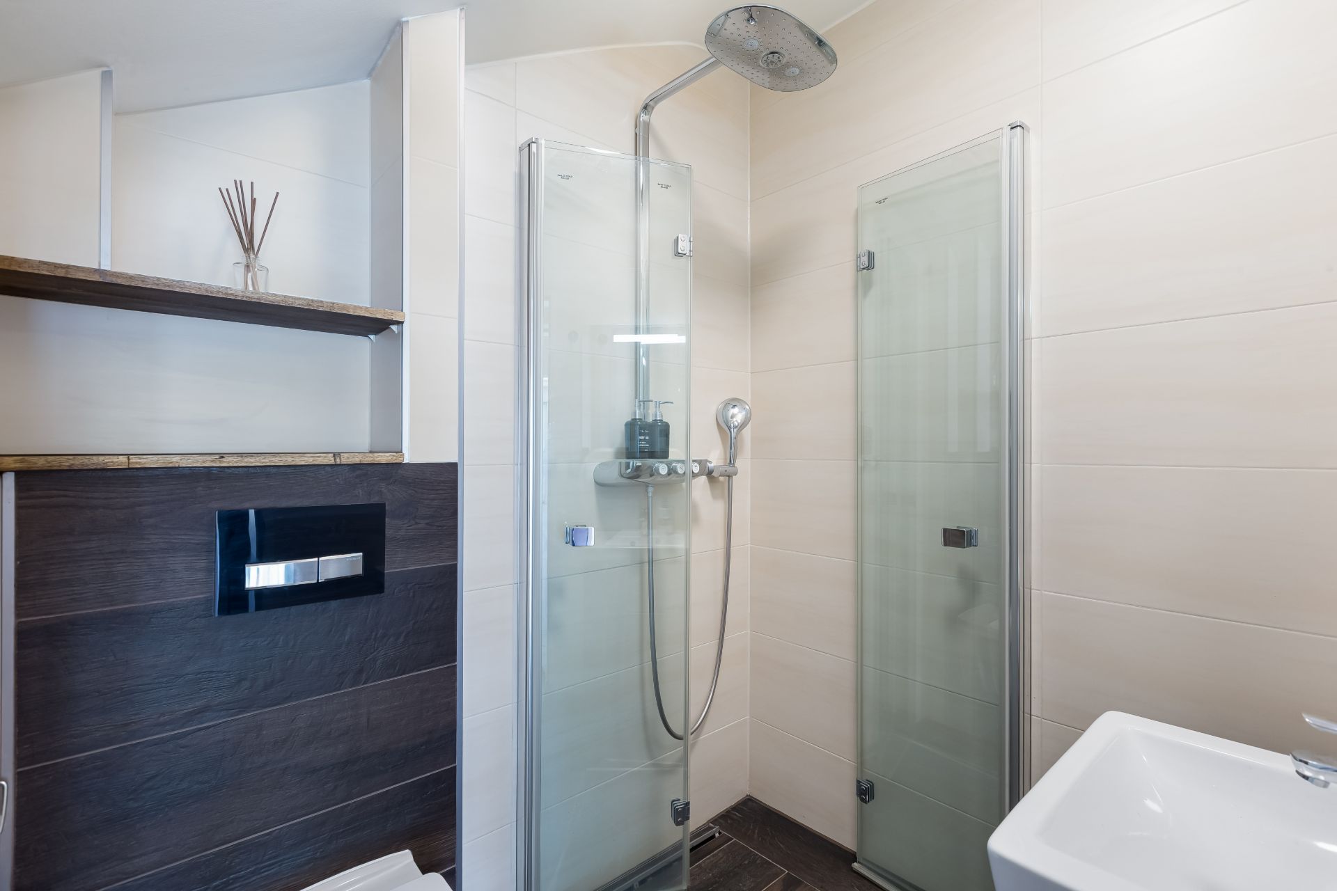Modernes Badezimmer mit Glasdusche, Wandregal und kleinem Waschbecken.