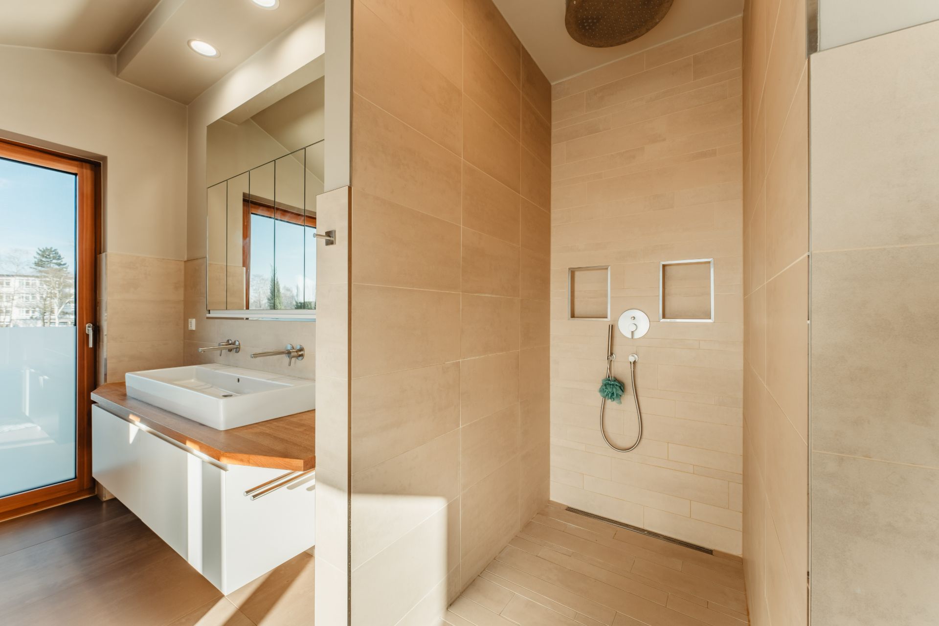 Modernes Badezimmer mit ebenerdiger Dusche und großem Waschbecken vor einem Spiegel.