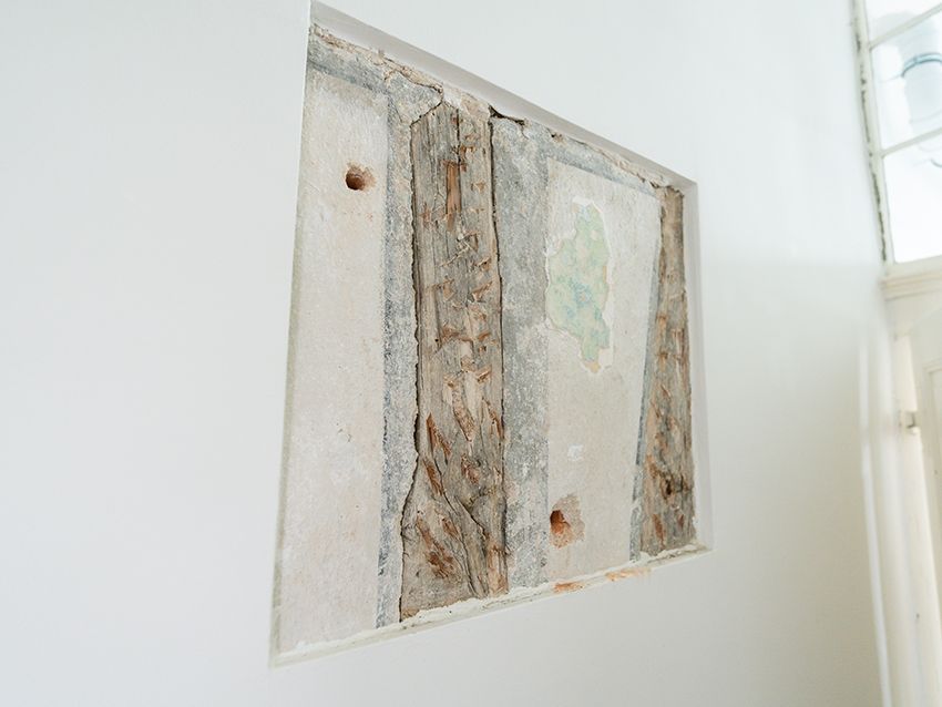 Ausschnitt einer Wand mit freigelegten Holz- und Putzstrukturen in einem Wohnraum.