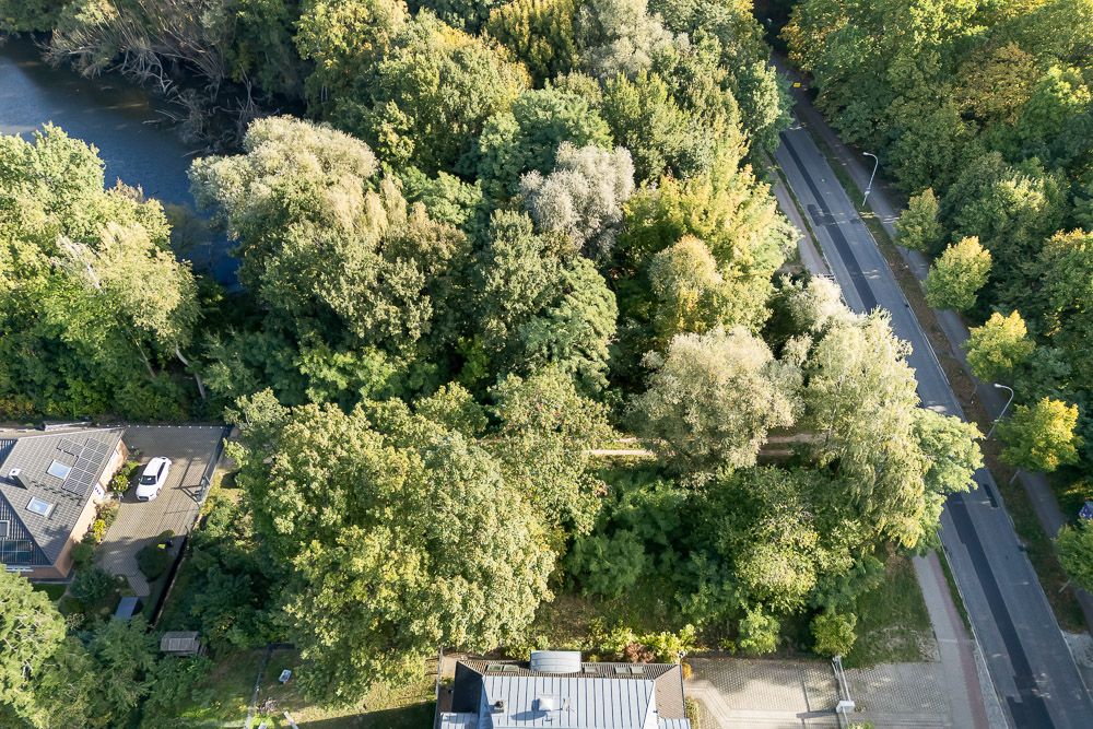 Luftaufnahme eines Hauses neben dichtem Wald, einer Straße und einem Fluss.