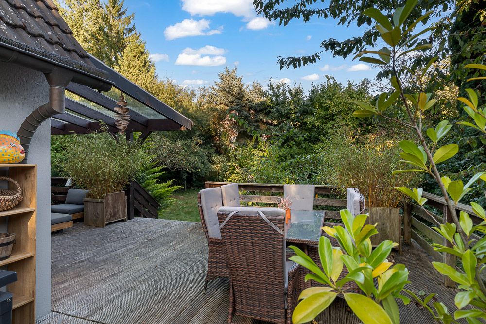 Holzterrasse mit Sitzgruppe und Pflanzen, Blick in den grünen Garten.