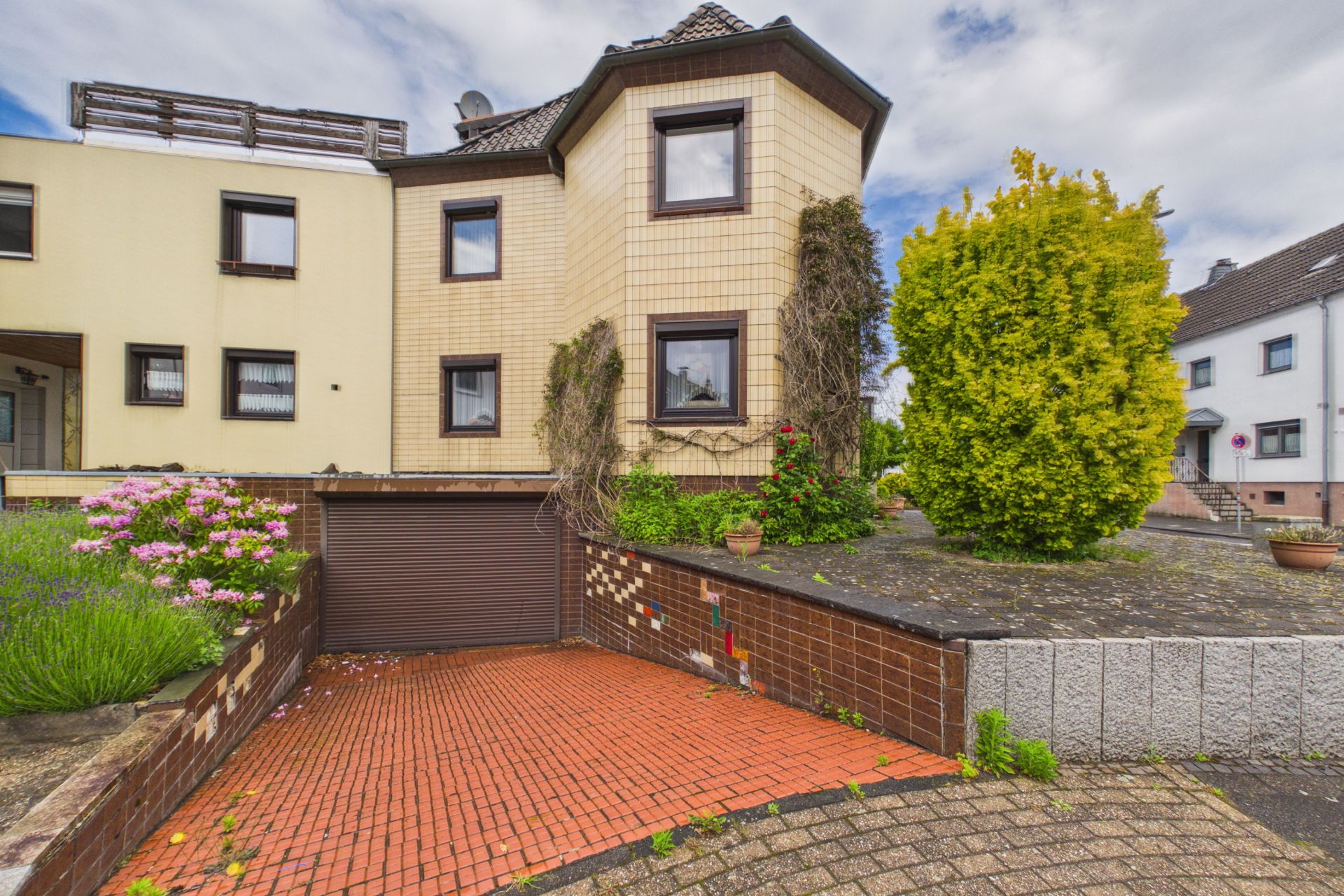 Einfamilienhaus mit Einfahrt, Garage und bepflanztem Vorgarten.