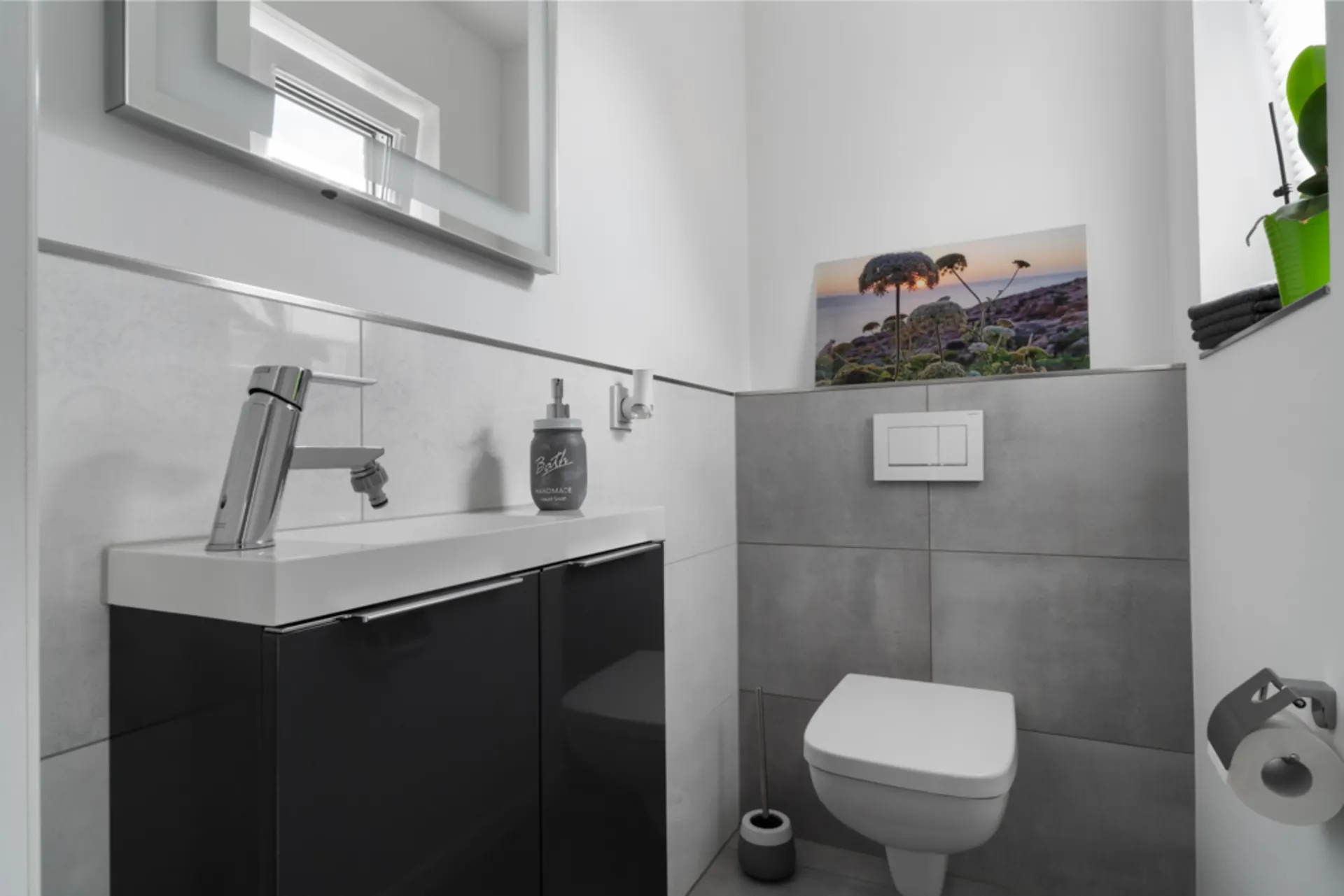 Modernes Badezimmer mit Wandtoilette, Waschbecken, Spiegel und Dekoration.