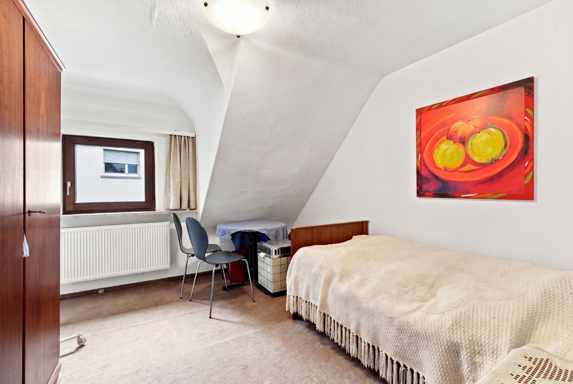 Kleines Schlafzimmer mit Einzelbett, Schrank, Schreibtisch und Fenster, Bild an der Wand.