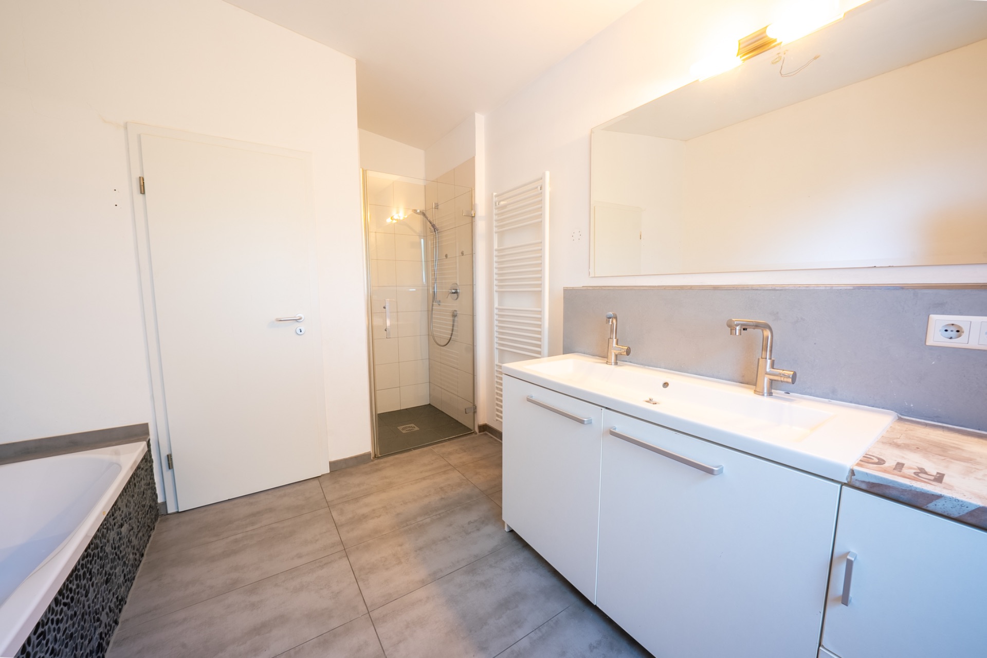Modernes Badezimmer mit Doppelwaschbecken, Dusche, Badewanne und großem Spiegel.