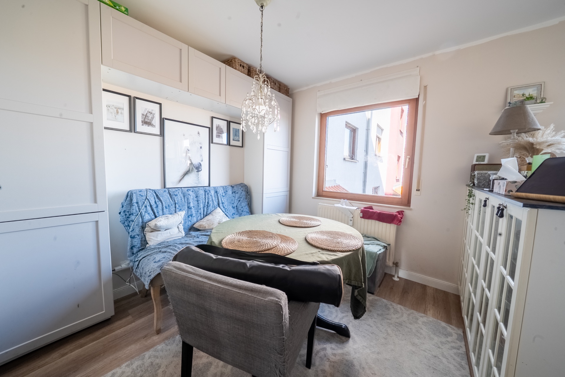 Heller Essbereich mit rundem Tisch, Sofa, Stuhl und großem Fenster in einem Wohnraum.