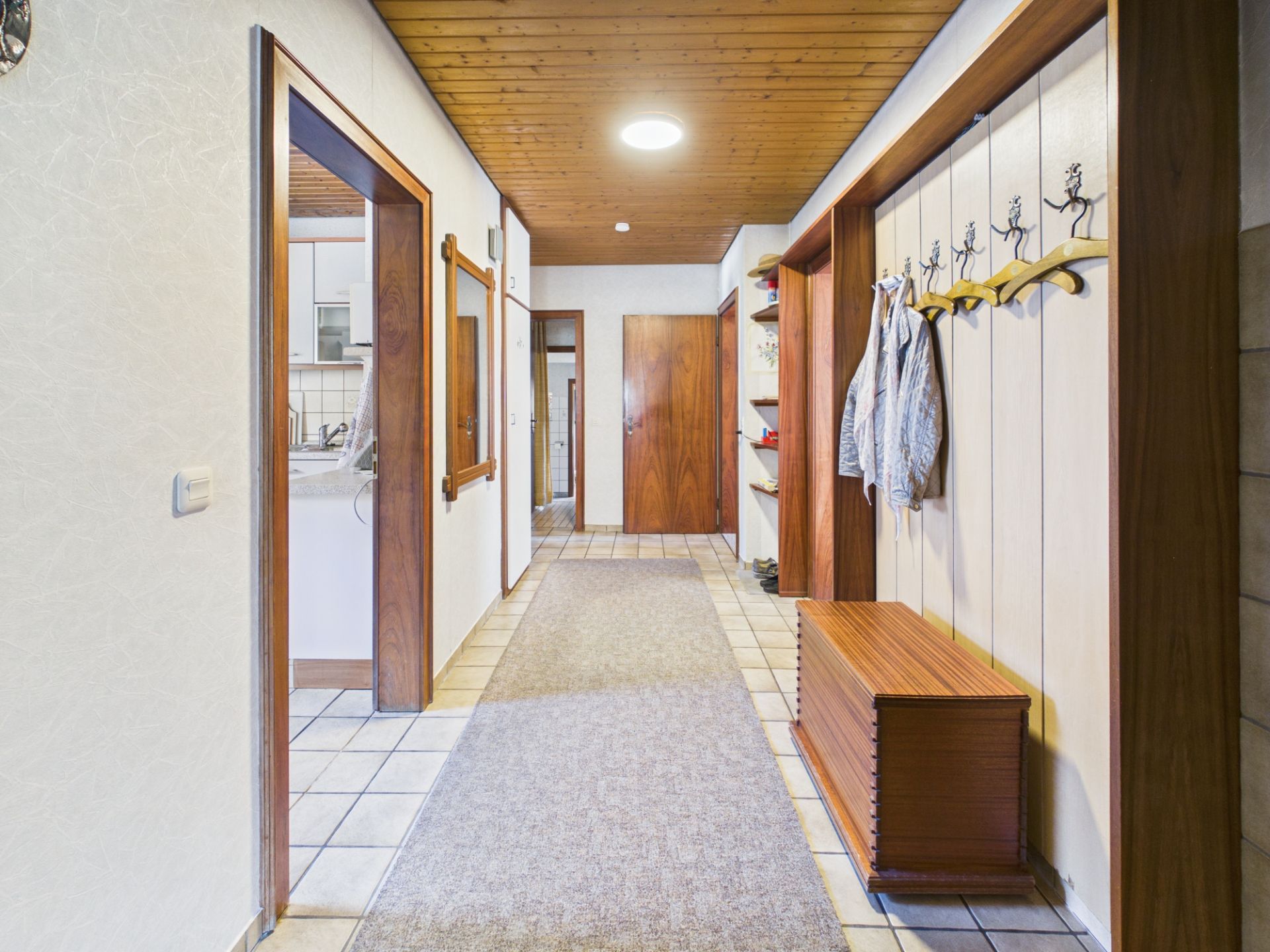Flur mit Holzdecke, Garderobe, Sitzbank und Türen zu anderen Räumen.