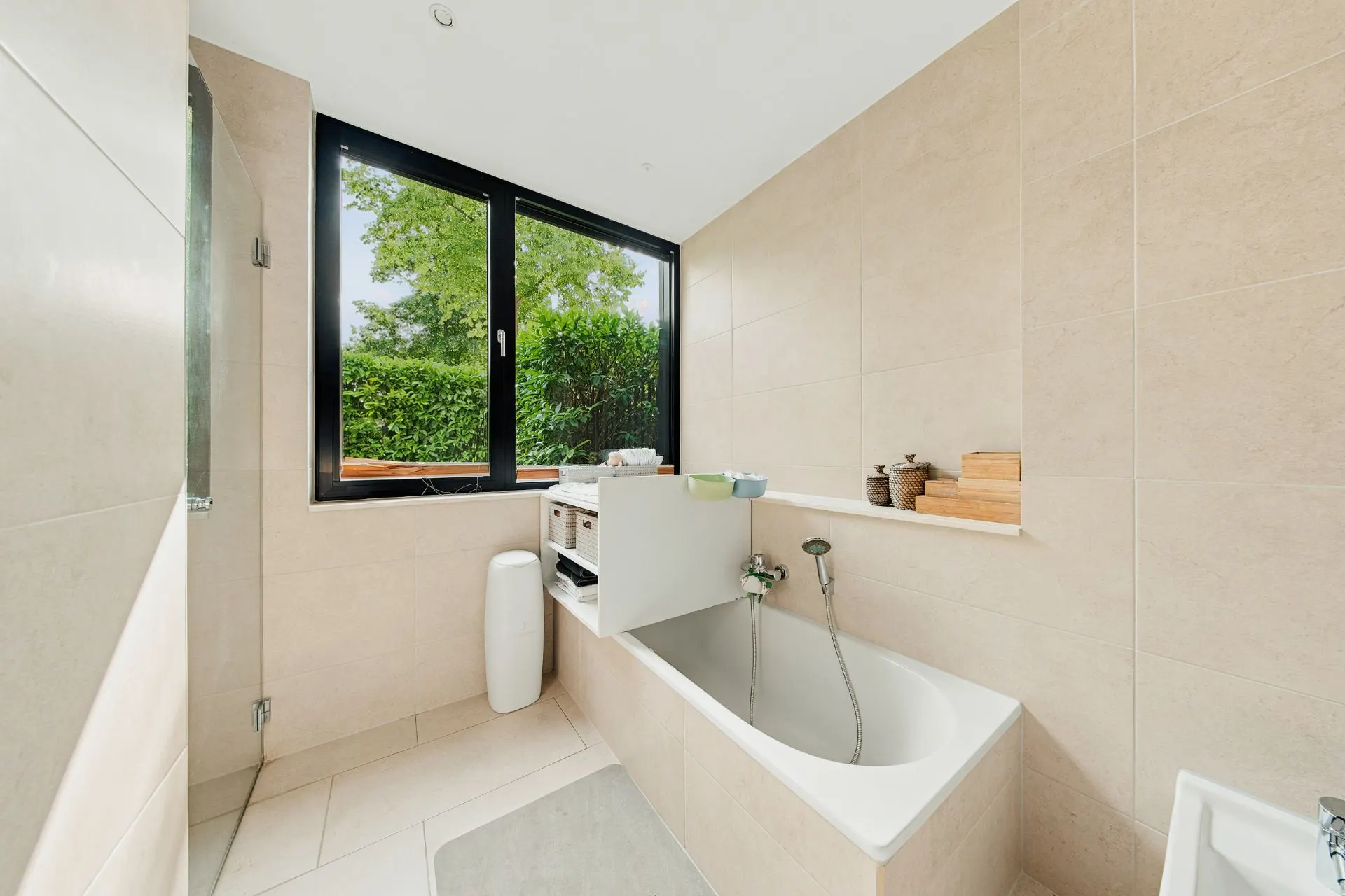 Modernes Badezimmer mit Badewanne, großem Fenster und beigen Fliesen.