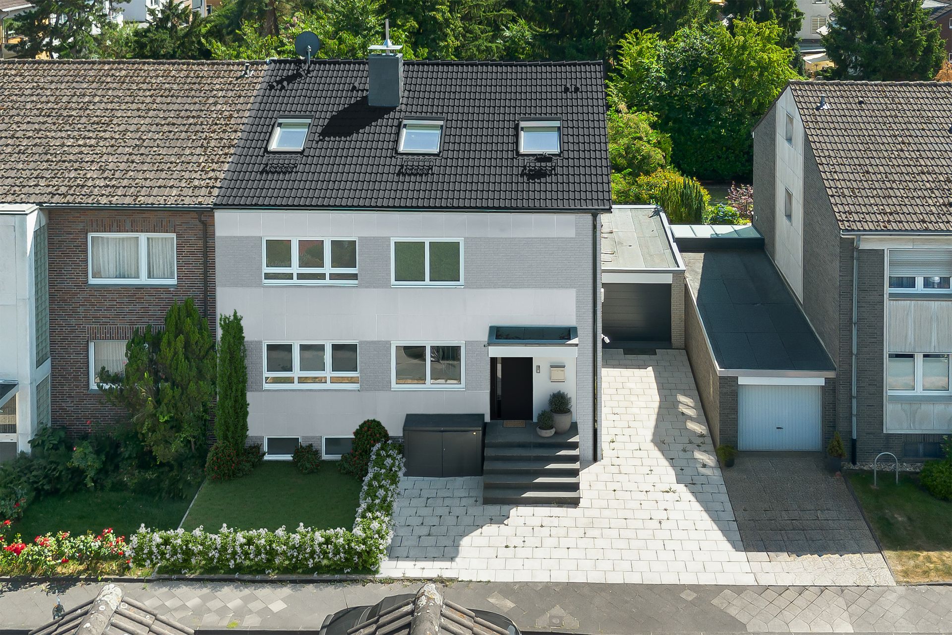 Modernes Reihenhaus mit Vorgarten, Treppe zum Eingang und Garage rechts, aus der Vogelperspektive.