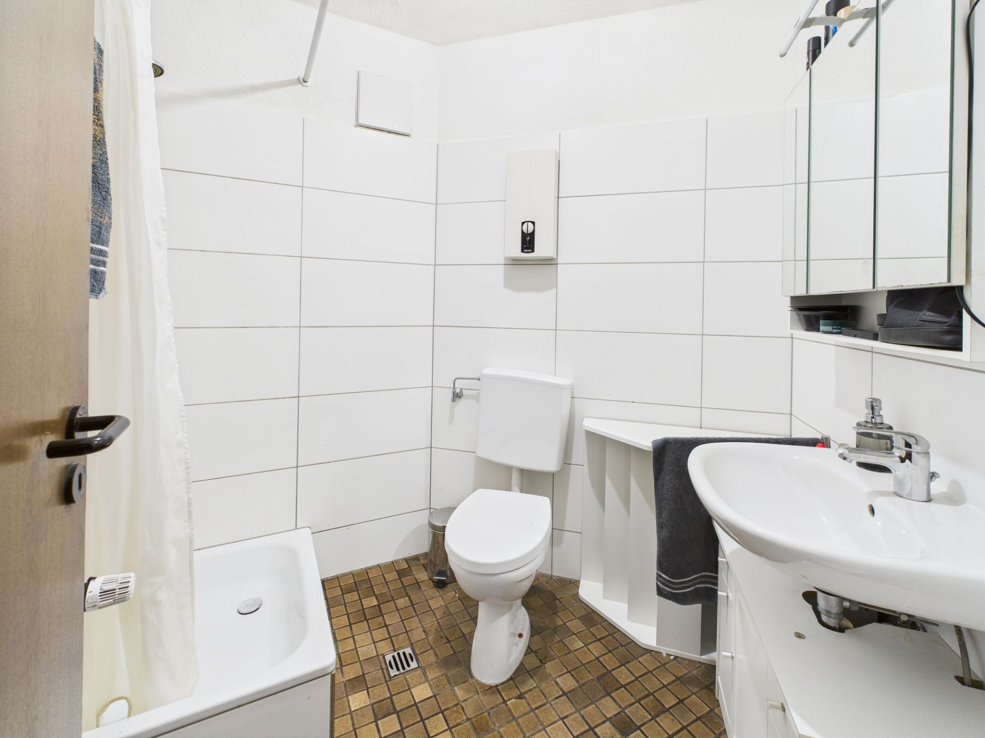 Helles Badezimmer mit Dusche, Toilette, Waschbecken und Spiegelschrank.