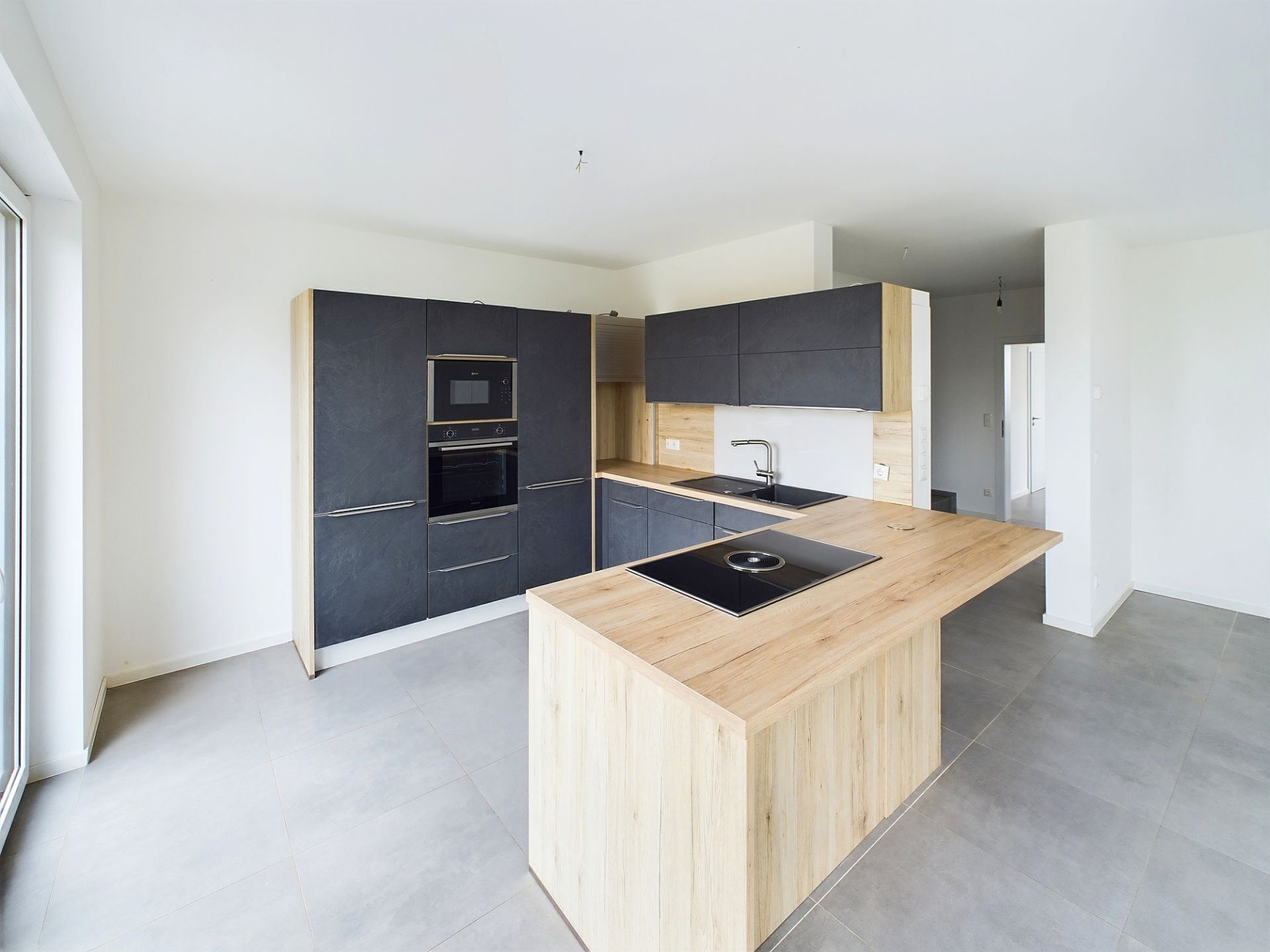 Moderne Einbauküche mit Holzarbeitsflächen, grauen Schränken, Herd und Backofen.