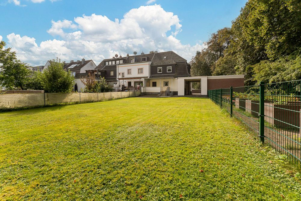 Großer grüner Garten mit Rasenfläche und angrenzendem Wohnhaus im Hintergrund.
