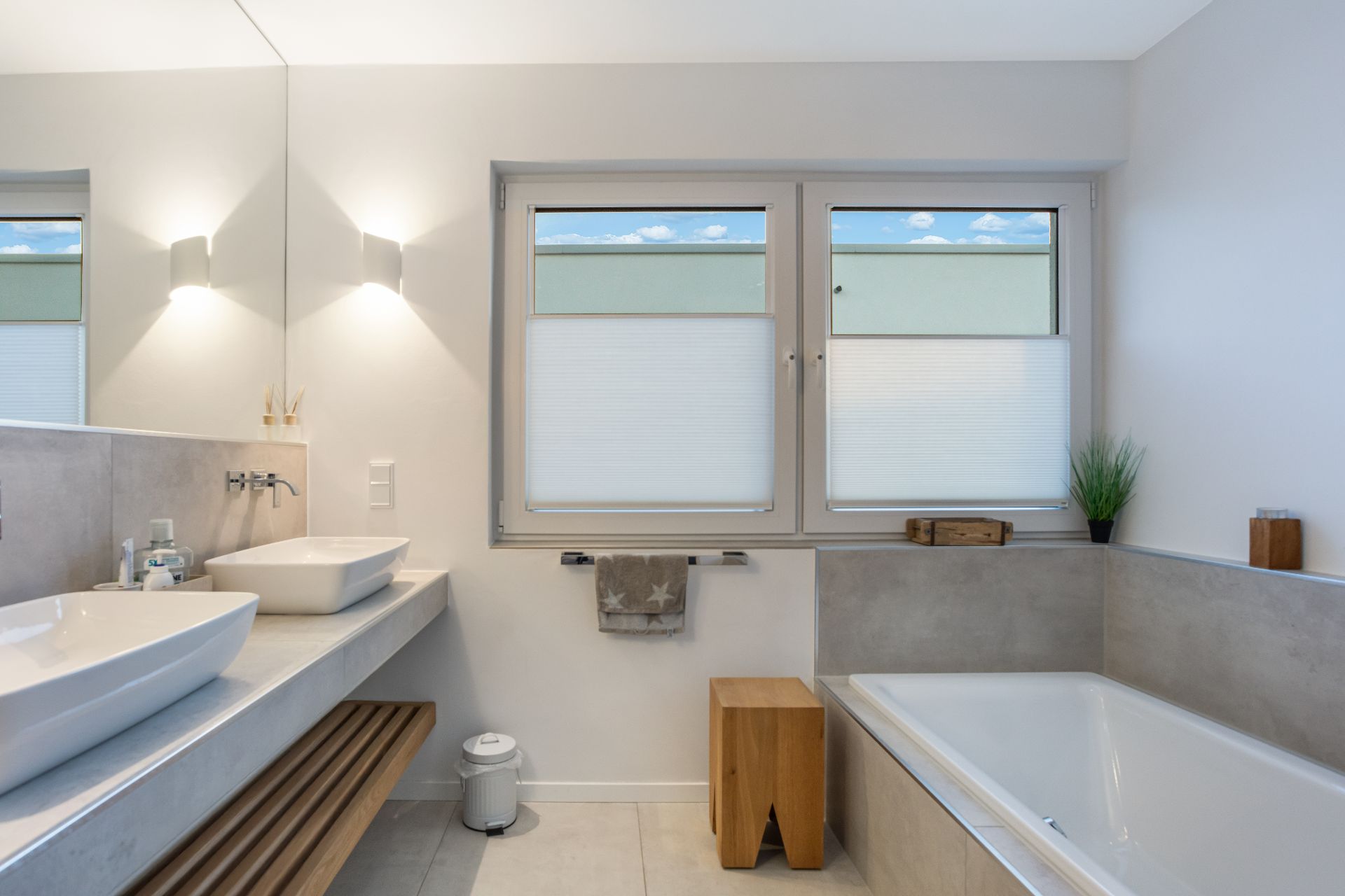 Modernes Badezimmer mit zwei Waschbecken, Badewanne, großem Spiegel und zwei Fenstern.