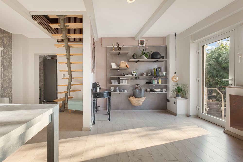 Helles Wohnzimmer mit Regalwand, Wendeltreppe und großer Glastür zum Garten.