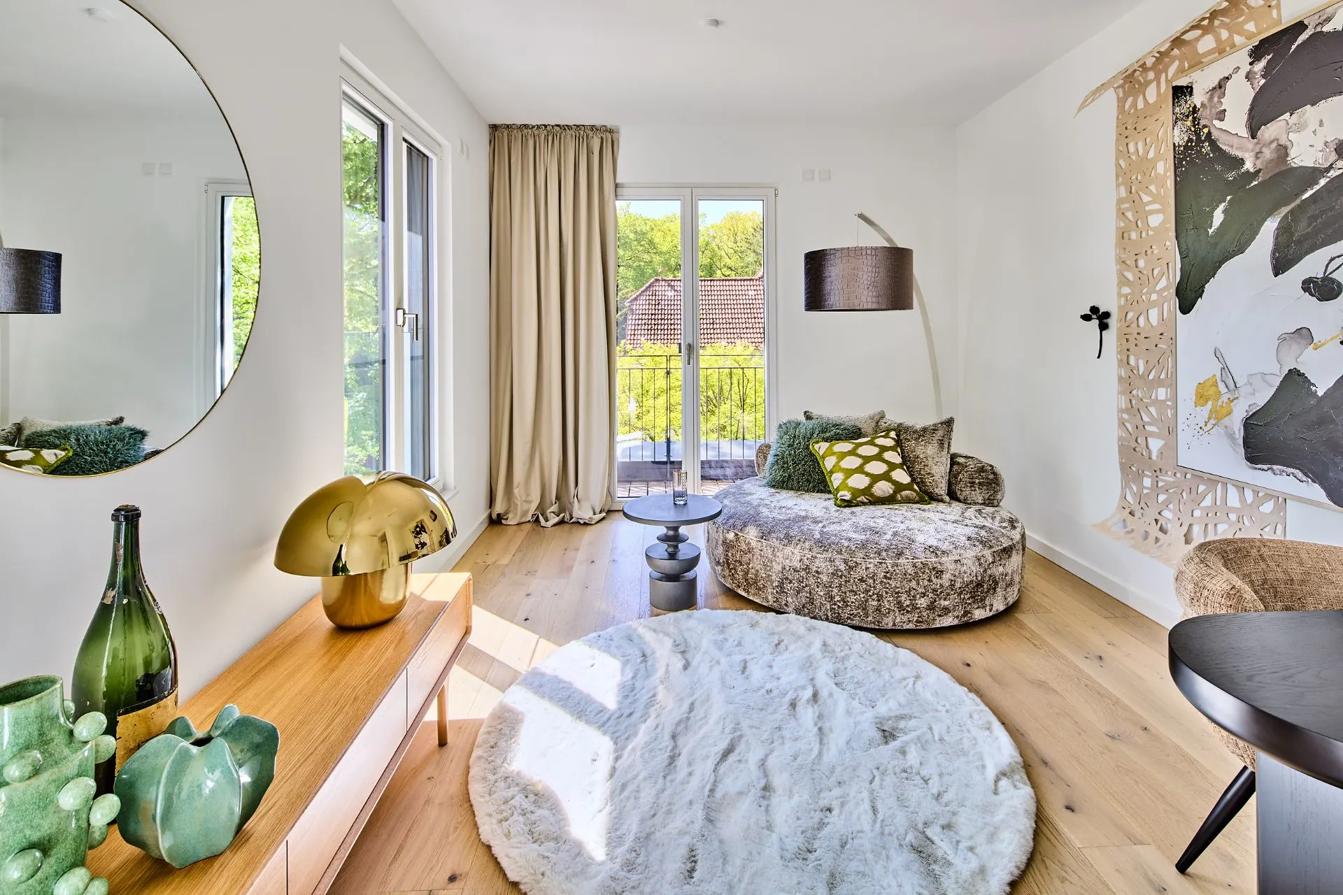 Helles Wohnzimmer mit rundem Teppich, Designersessel, Sideboard, Dekovasen und großem Wandspiegel.
