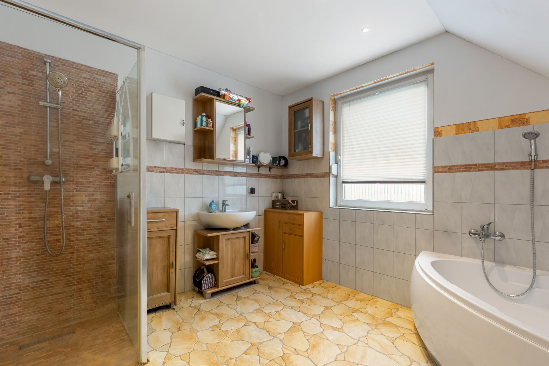 Modernes Badezimmer mit Dusche, Badewanne, Waschtisch, Fenstern und Schränken.