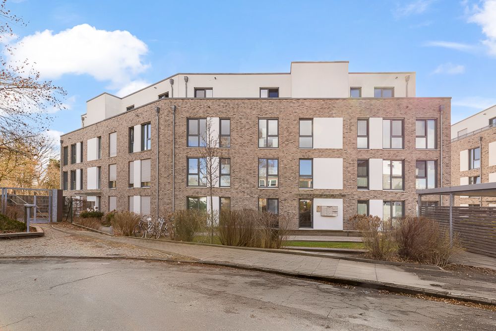 Modernes dreistöckiges Wohngebäude mit großen Fenstern und Ziegel-Fassade.