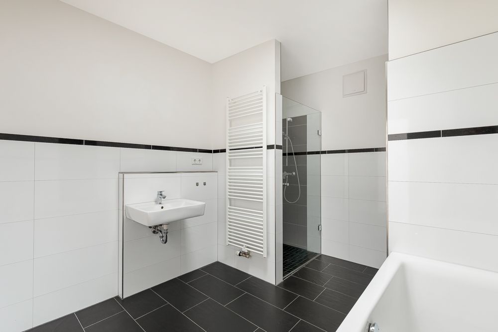 Modernes Bad mit Waschbecken, Handtuchheizkörper, Dusche und Badewanne.