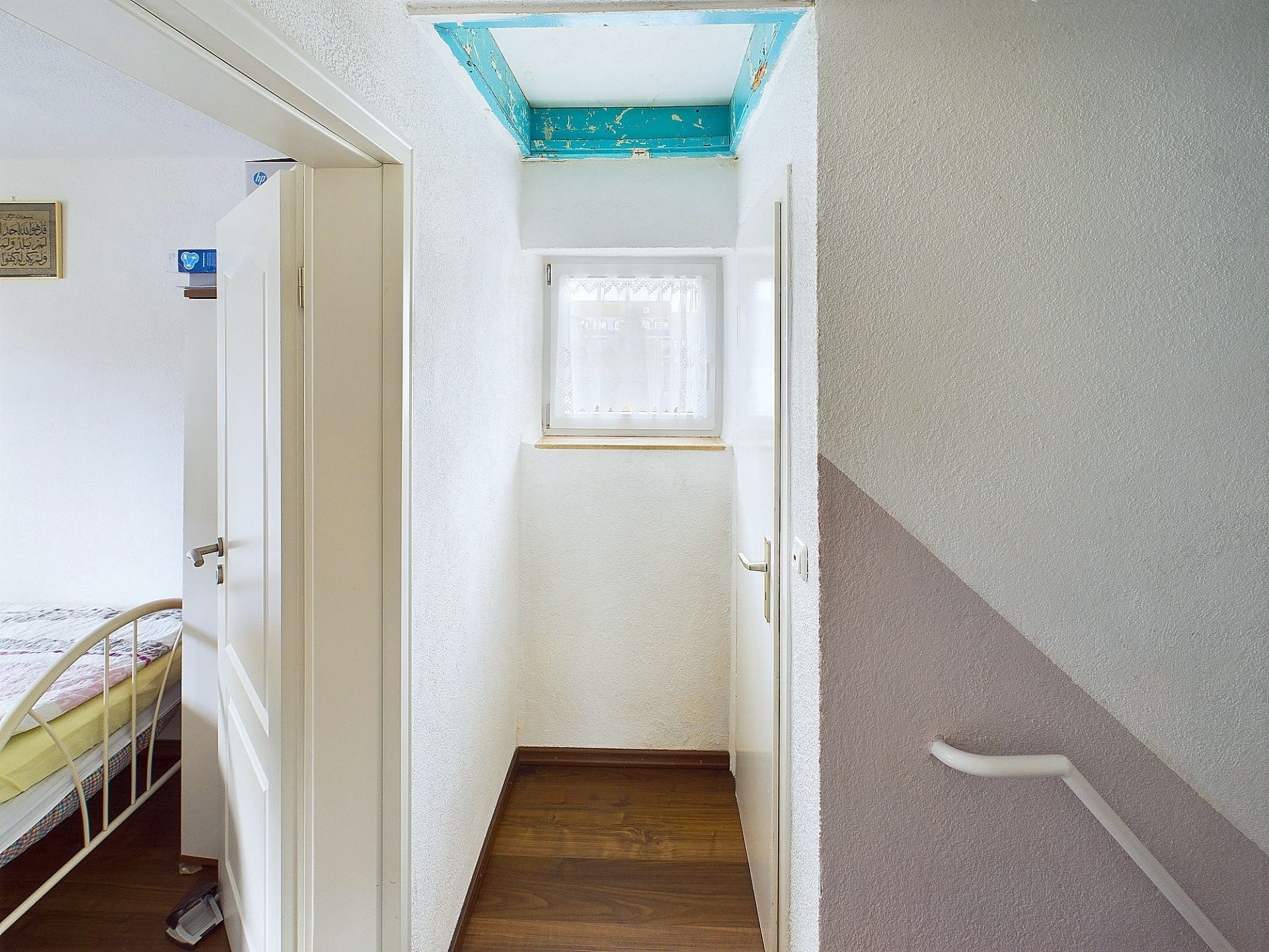 Heller Flur mit Fenster, Türen zu Schlafzimmer und Treppenaufgang, Holzboden.