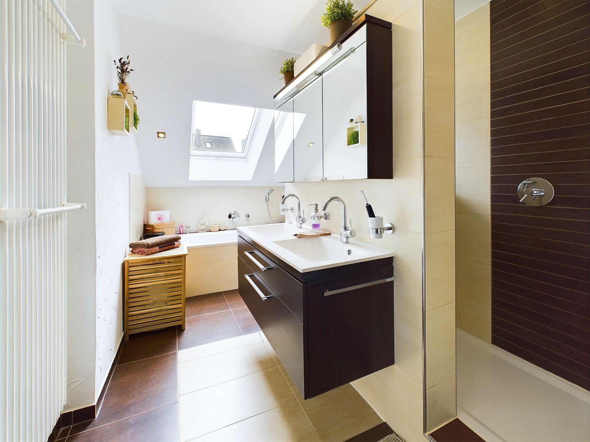 Modernes Badezimmer mit Doppelwaschbecken, großer Spiegelwand und Dusche, Tageslicht durch Dachfenster.