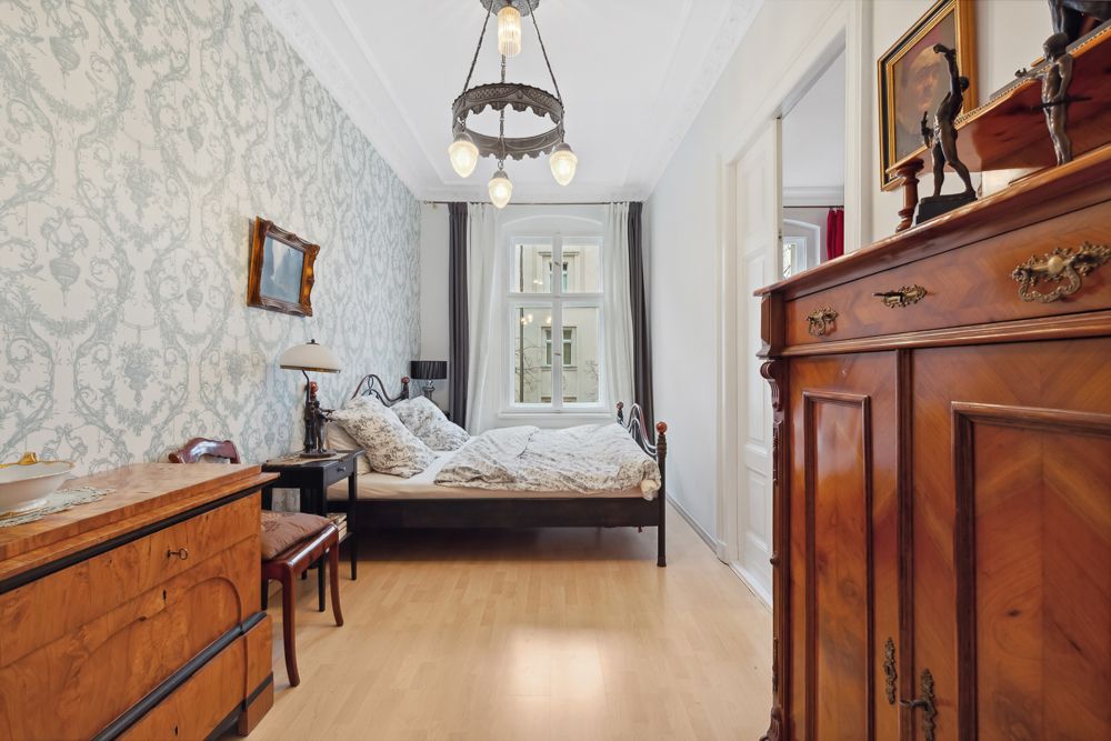 Schlafzimmer mit Doppelbett, Holzmöbeln, Tapete und großem Fenster.
