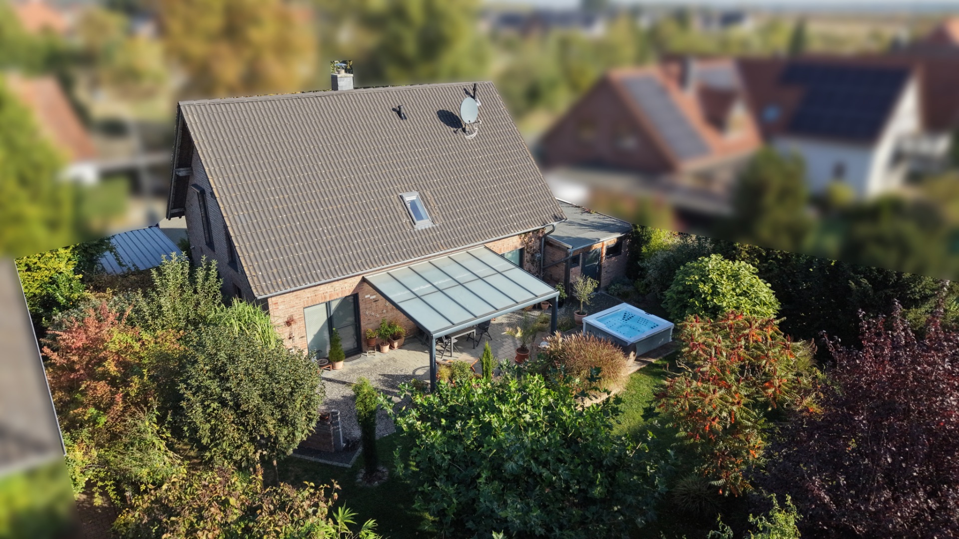 Einfamilienhaus mit Wintergarten und Whirlpool im grünen Garten, aus der Vogelperspektive gesehen.