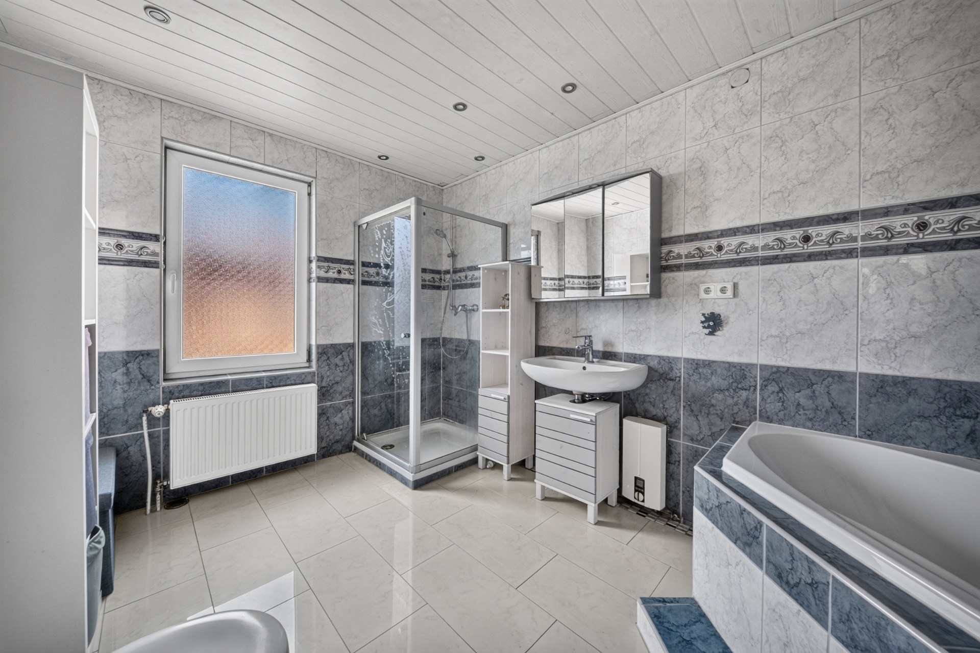 Modernes Badezimmer mit Dusche, Badewanne, Waschbecken und großem Fenster.