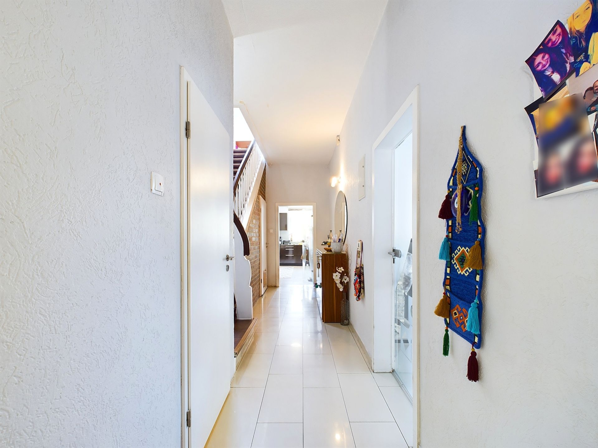 Heller Flur mit weißen Türen, Treppe und Wanddeko in einem Wohnhaus.