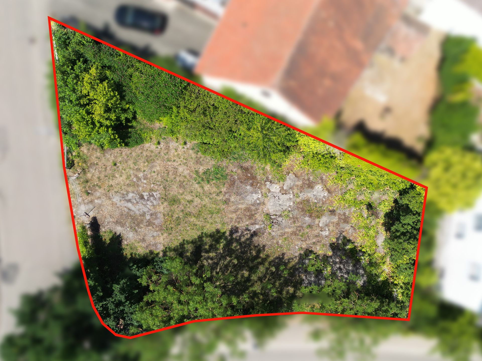 Luftaufnahme eines unbebauten, unregelmäßig begrenzten Grundstücks mit Gras und Sträuchern.