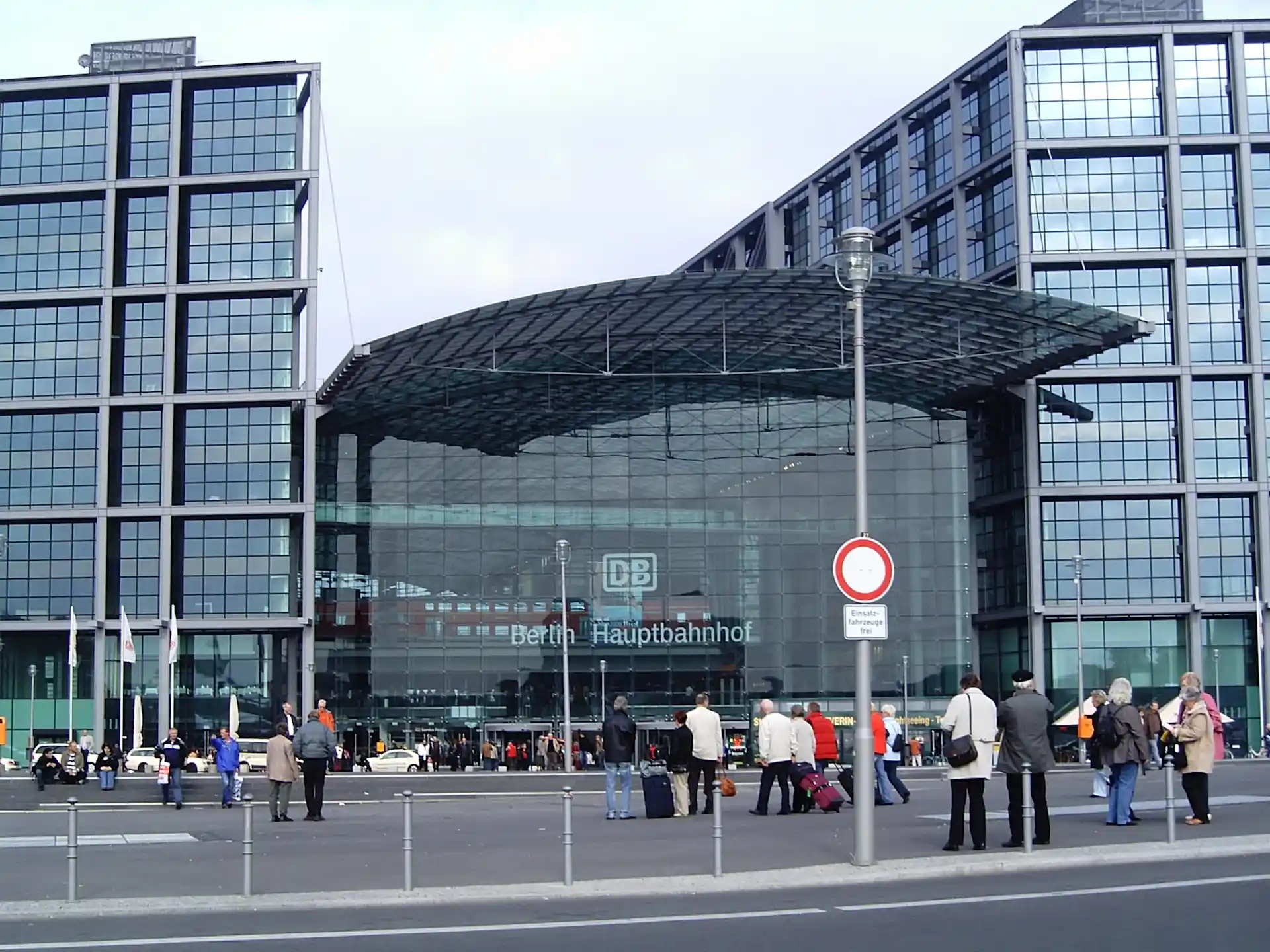 Großes, modernes Gebäude mit Glasfassade und vielen Menschen davor.