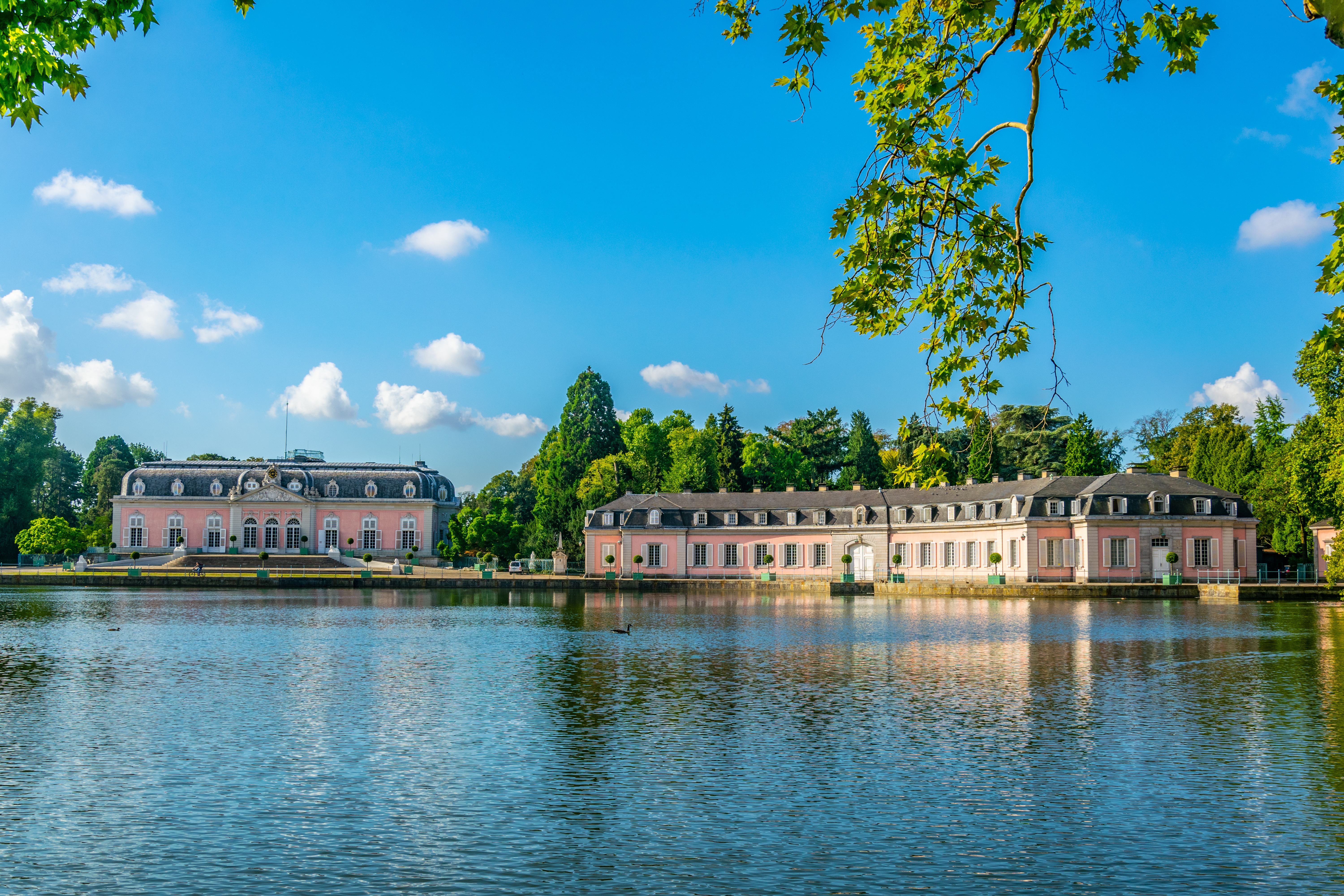 Historisches, rosafarbenes Gebäude mit vielen Fenstern und lila Blumenbeet im Vordergrund.
