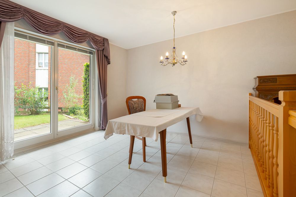 Esszimmer mit großem Fenster, Tisch, Stuhl, Kronleuchter und Blick in den Garten.