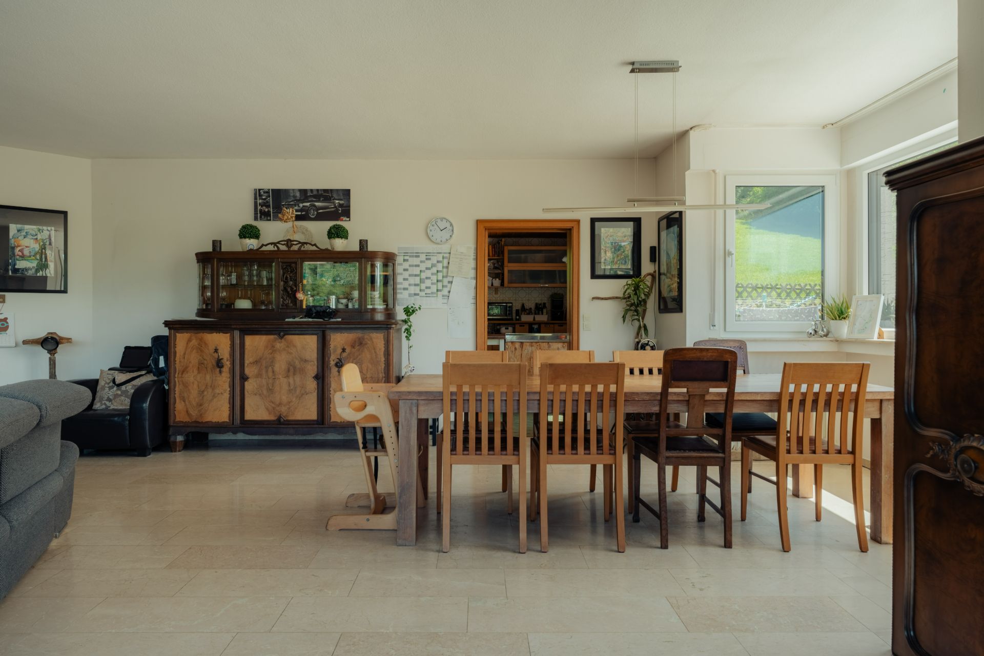 Essbereich mit großem Holztisch, mehreren Stühlen und einem Sideboard in einem hellen Raum.