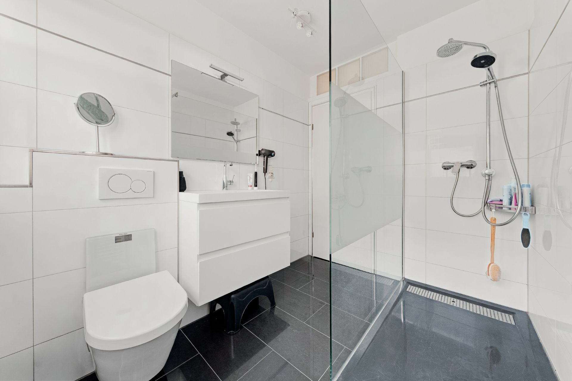 Modernes Badezimmer mit begehbarer Dusche, Toilette, Waschbecken und großem Spiegel.