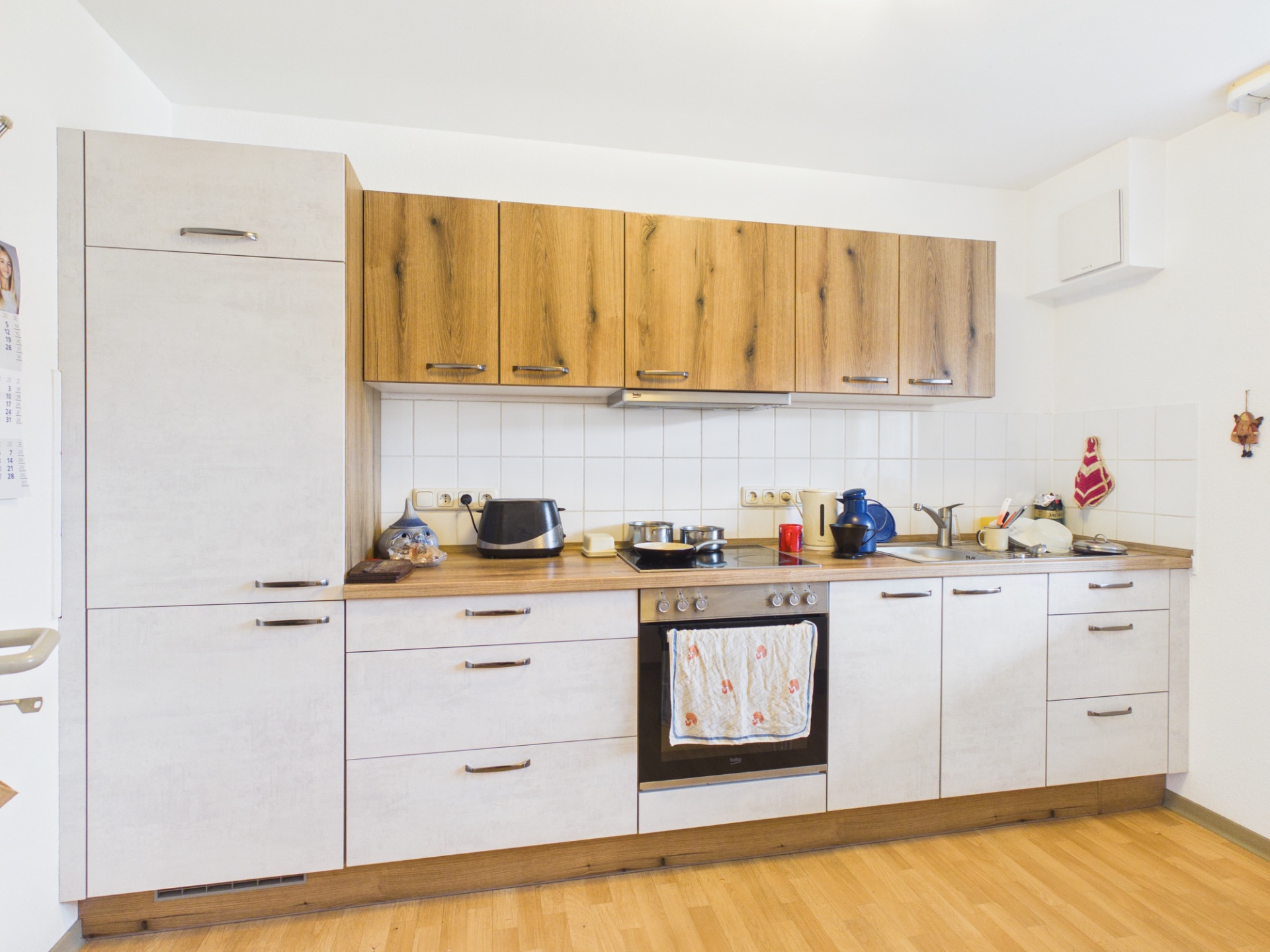 Moderne Küche mit Holzfronten, Herd, Spüle und Küchengeräten auf der Arbeitsplatte.