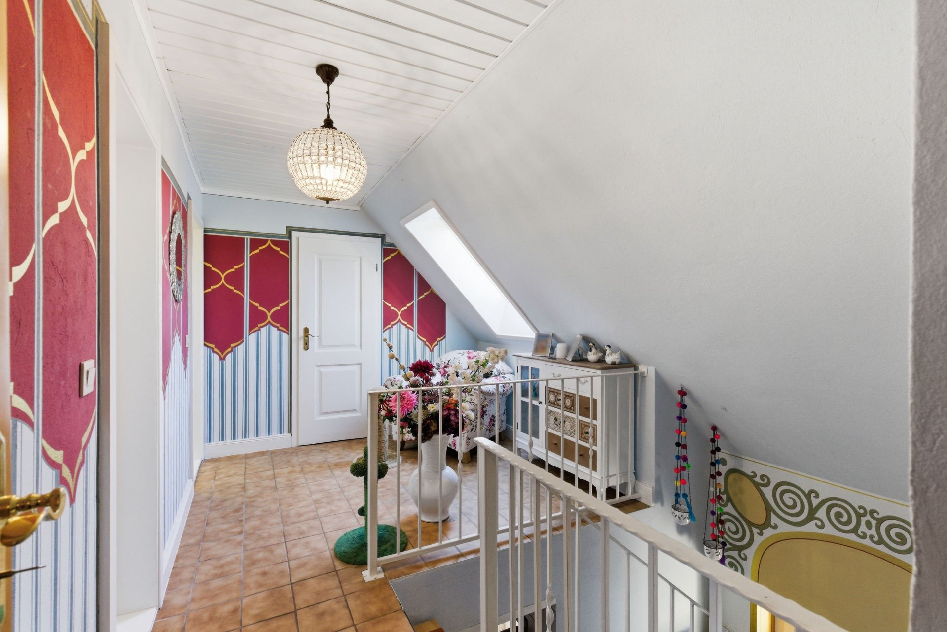 Heller Flur mit Fliesenboden, bunter Wanddeko, Treppe und weißen Türen.