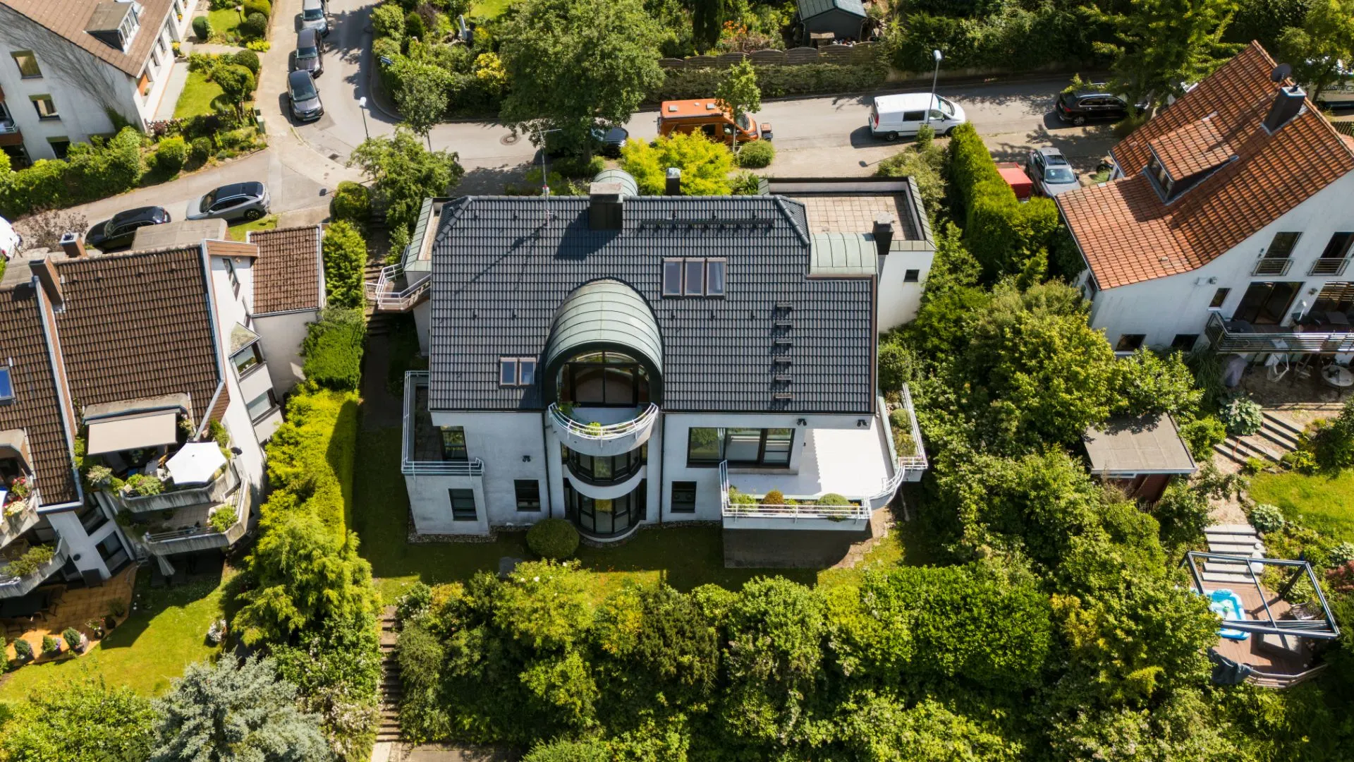 Luftaufnahme eines modernen Wohnhauses mit Garten und umliegenden Häusern.