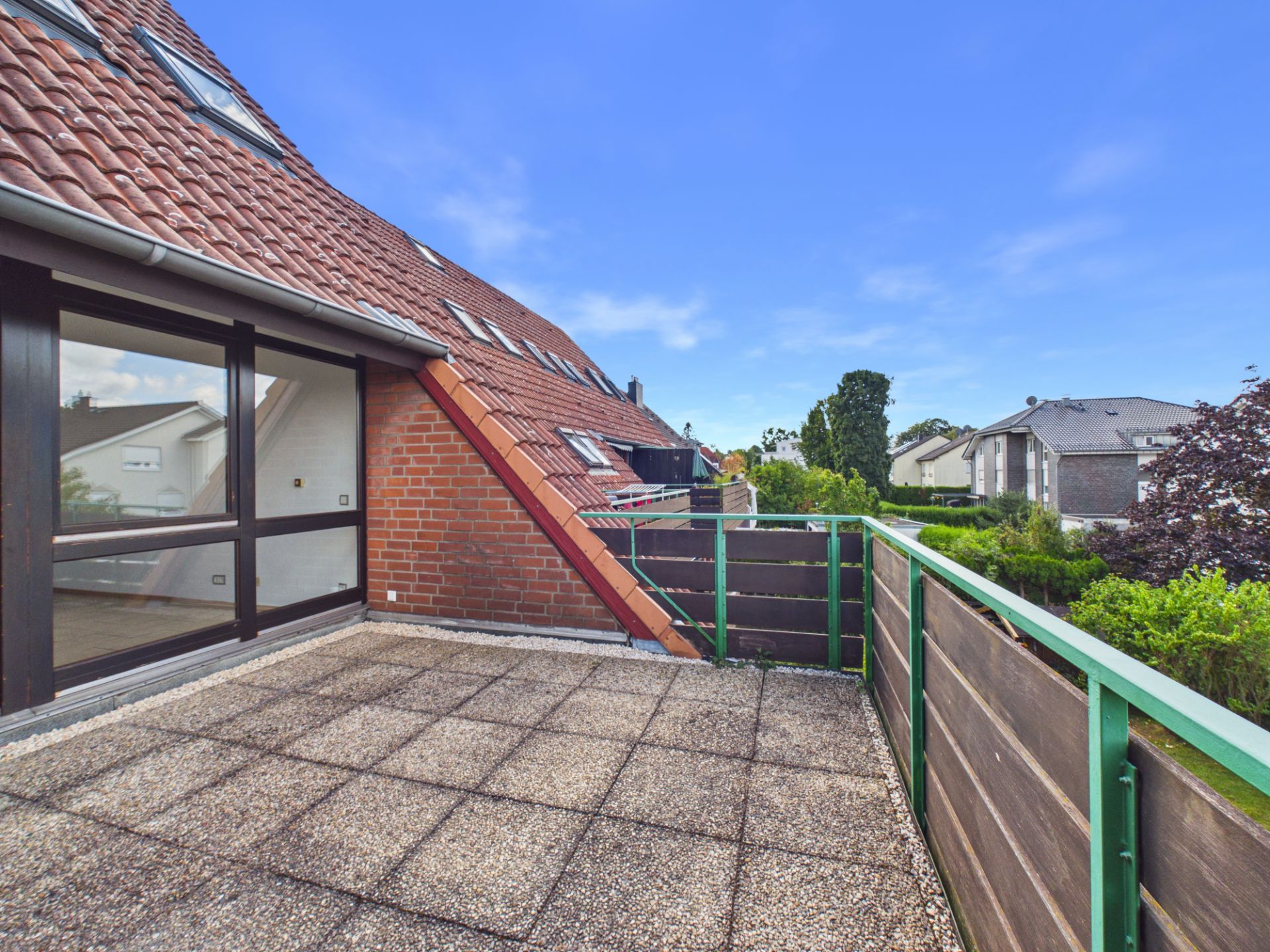 Große Dachterrasse mit Fliesenboden und Blick auf Nachbarhäuser und Gärten.