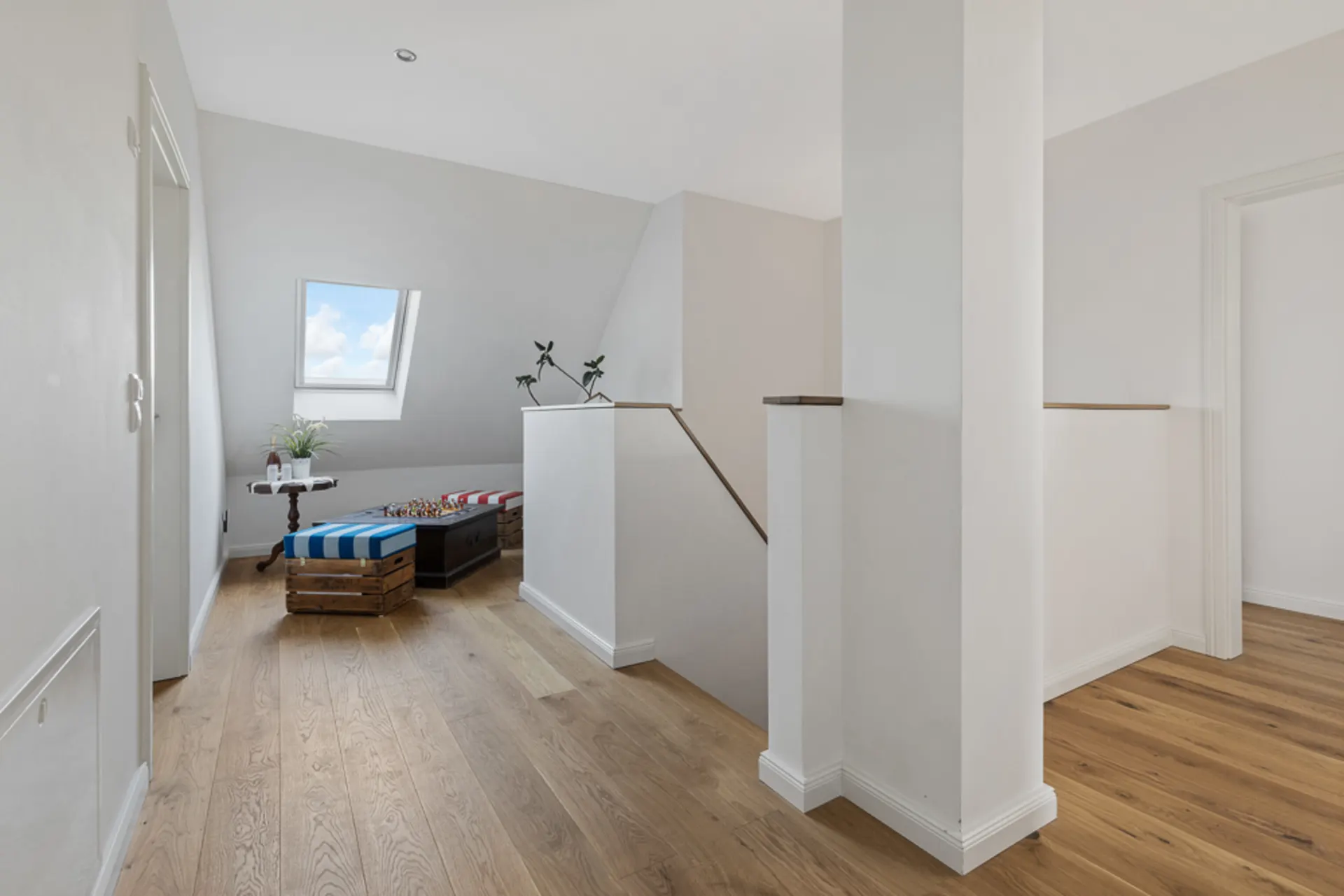 Heller Flur mit Holzfußboden, Sitzbank und Dachfenster, Pflanze auf kleinem Tisch.