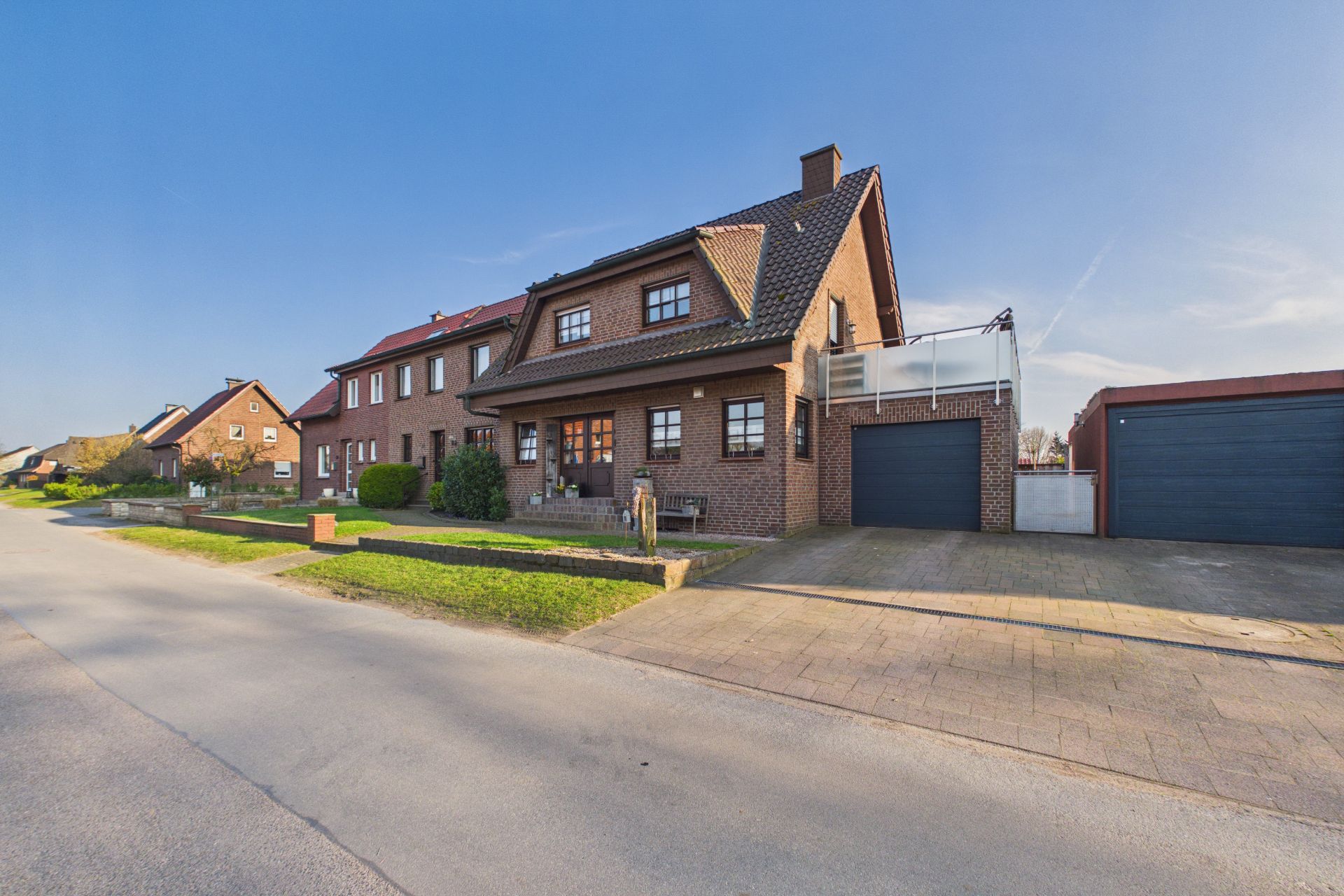 Zweistöckiges Backsteinhaus mit Garage und Vorgarten an einer ruhigen Wohnstraße.