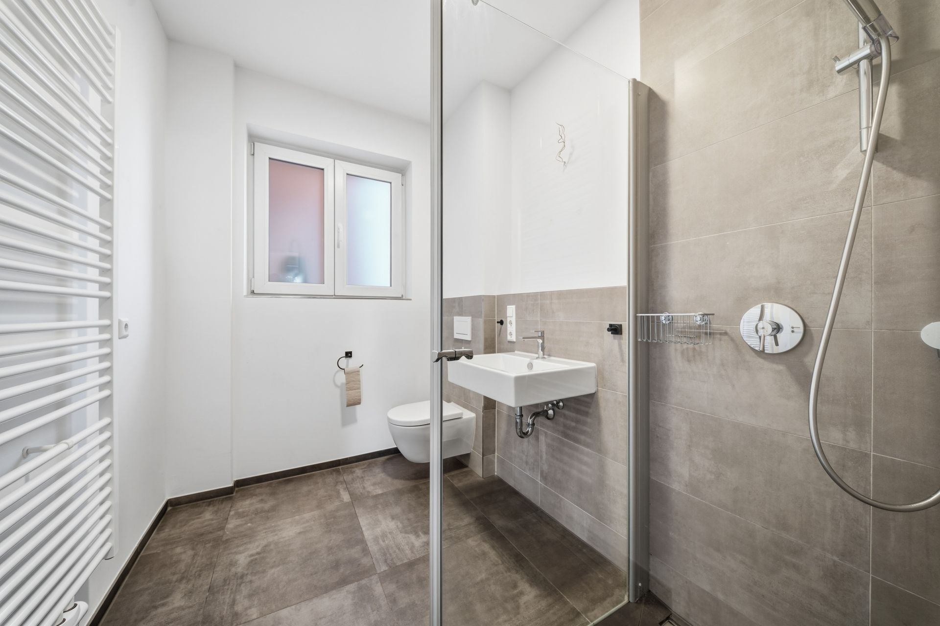Modernes Badezimmer mit Dusche, Waschbecken, Toilette und Fenster.