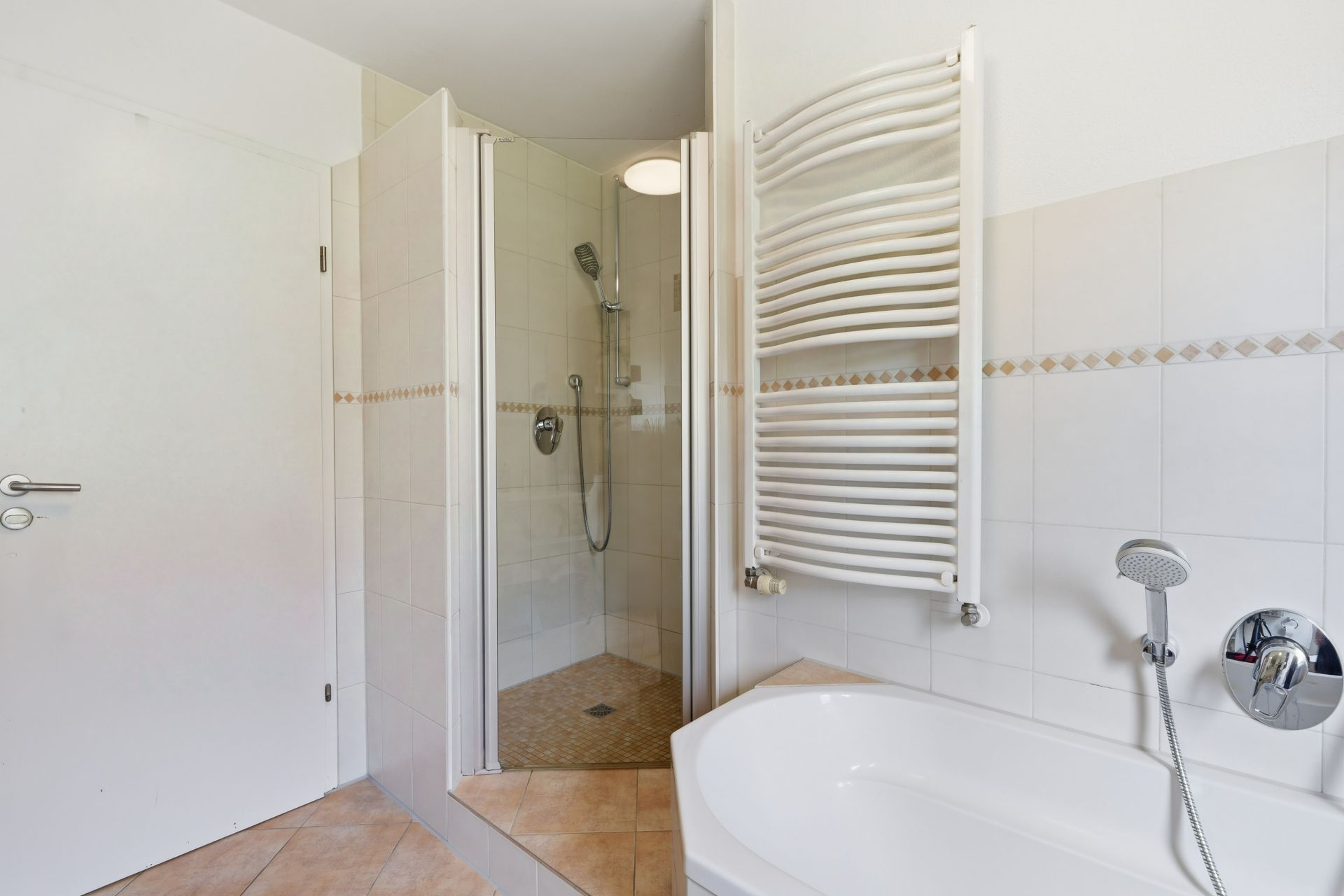 Badezimmer mit Dusche, Badewanne und weißem Handtuchheizkörper.