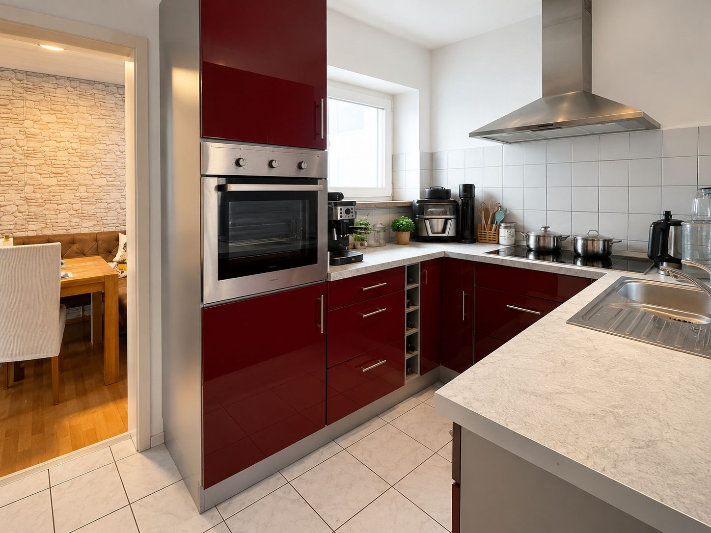 Moderne Küche mit roten Schränken, Geräten, Spüle und Durchgang zum Esszimmer.