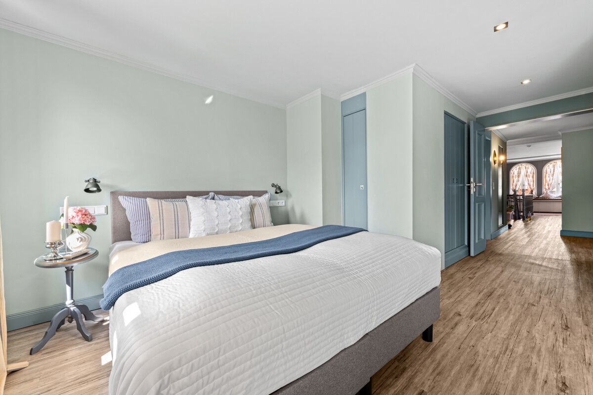 Helles Schlafzimmer mit Doppelbett, Nachttisch und Holzfußboden.