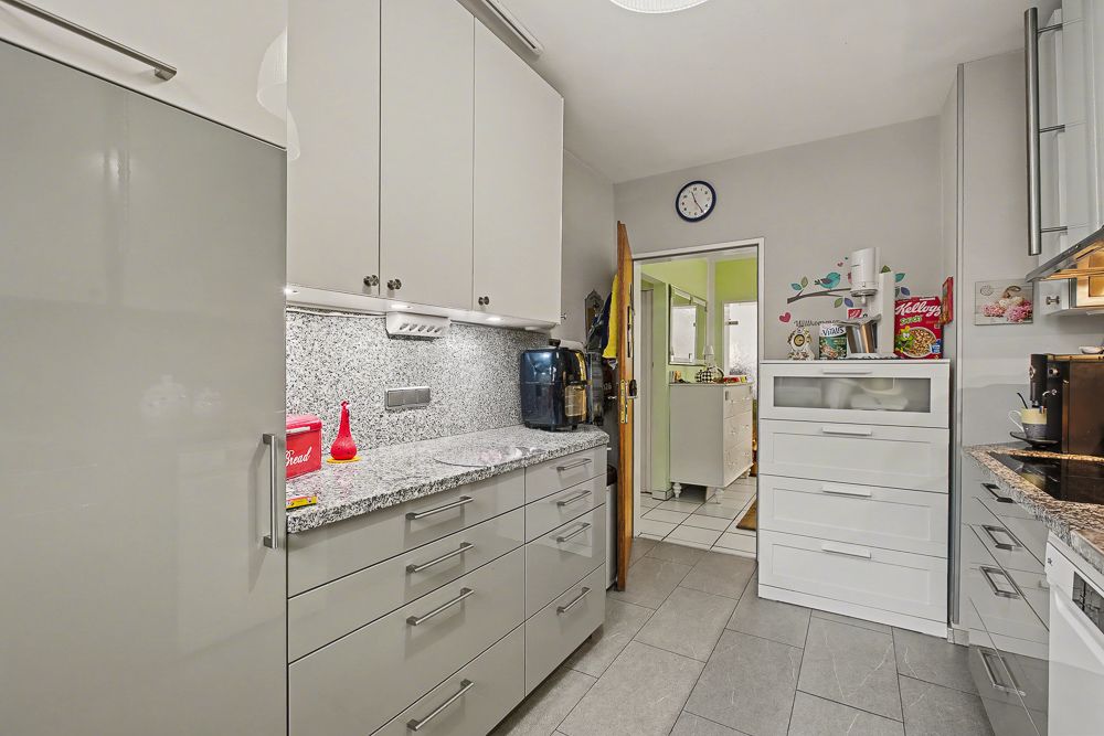 Moderne Küche mit grauen Schränken, Granit-Arbeitsplatte und Küchengeräten.