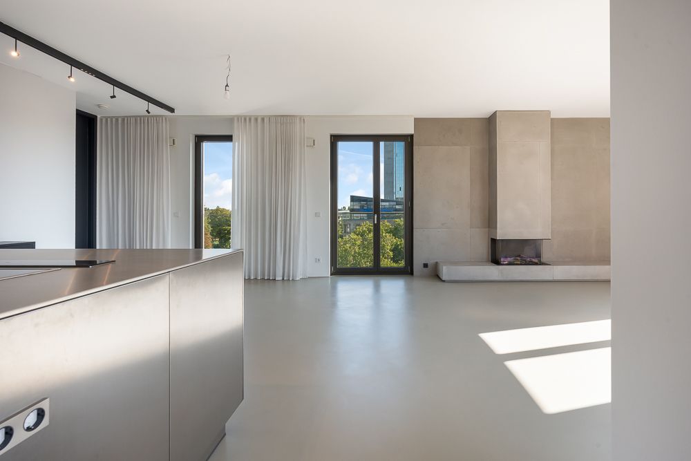 Heller, moderner Wohnraum mit großen Fenstern, Vorhängen und Kamin.