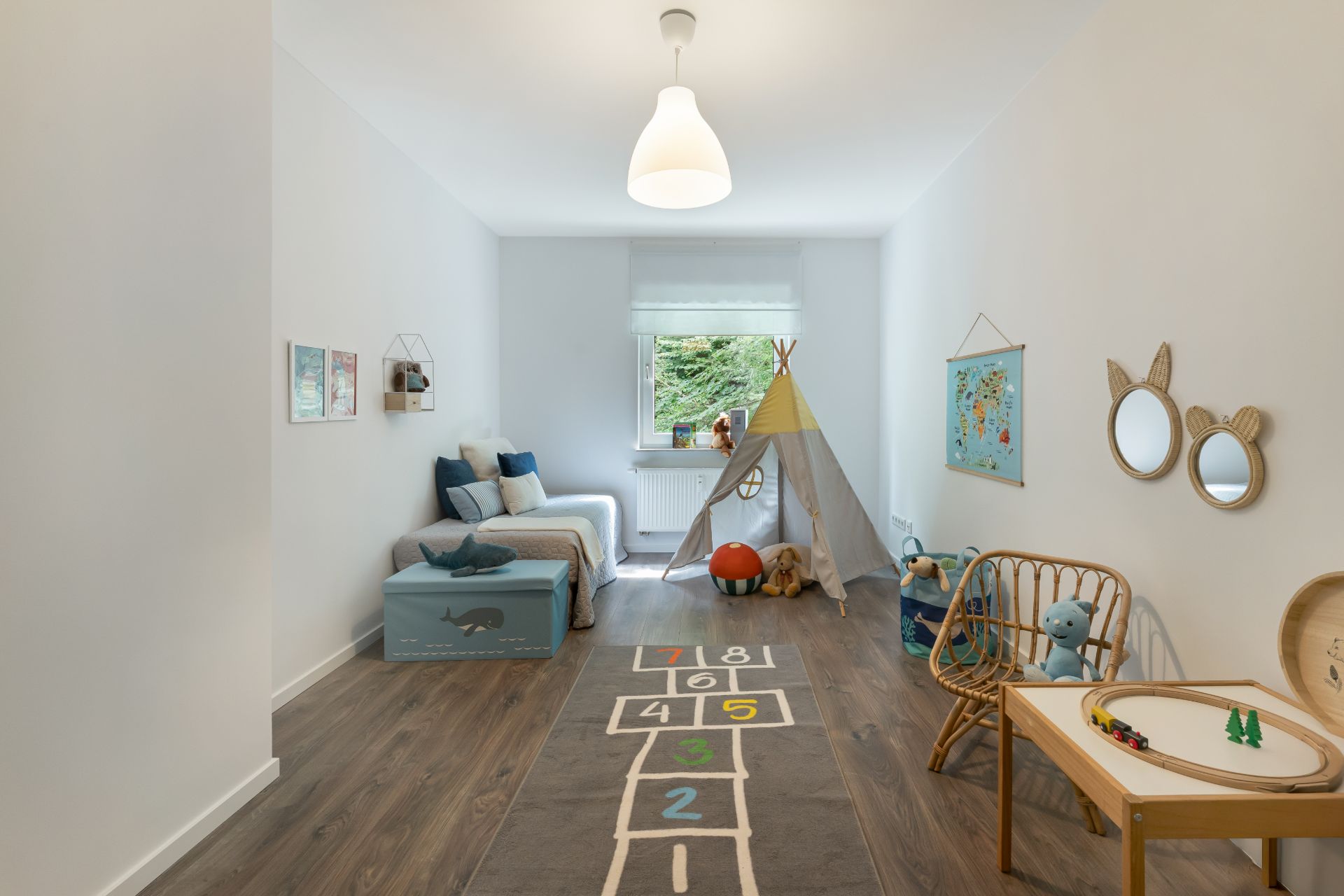 Helles Kinderzimmer mit Bett, Spielecke, Tipi-Zelt und Fenster mit Blick ins Grüne.