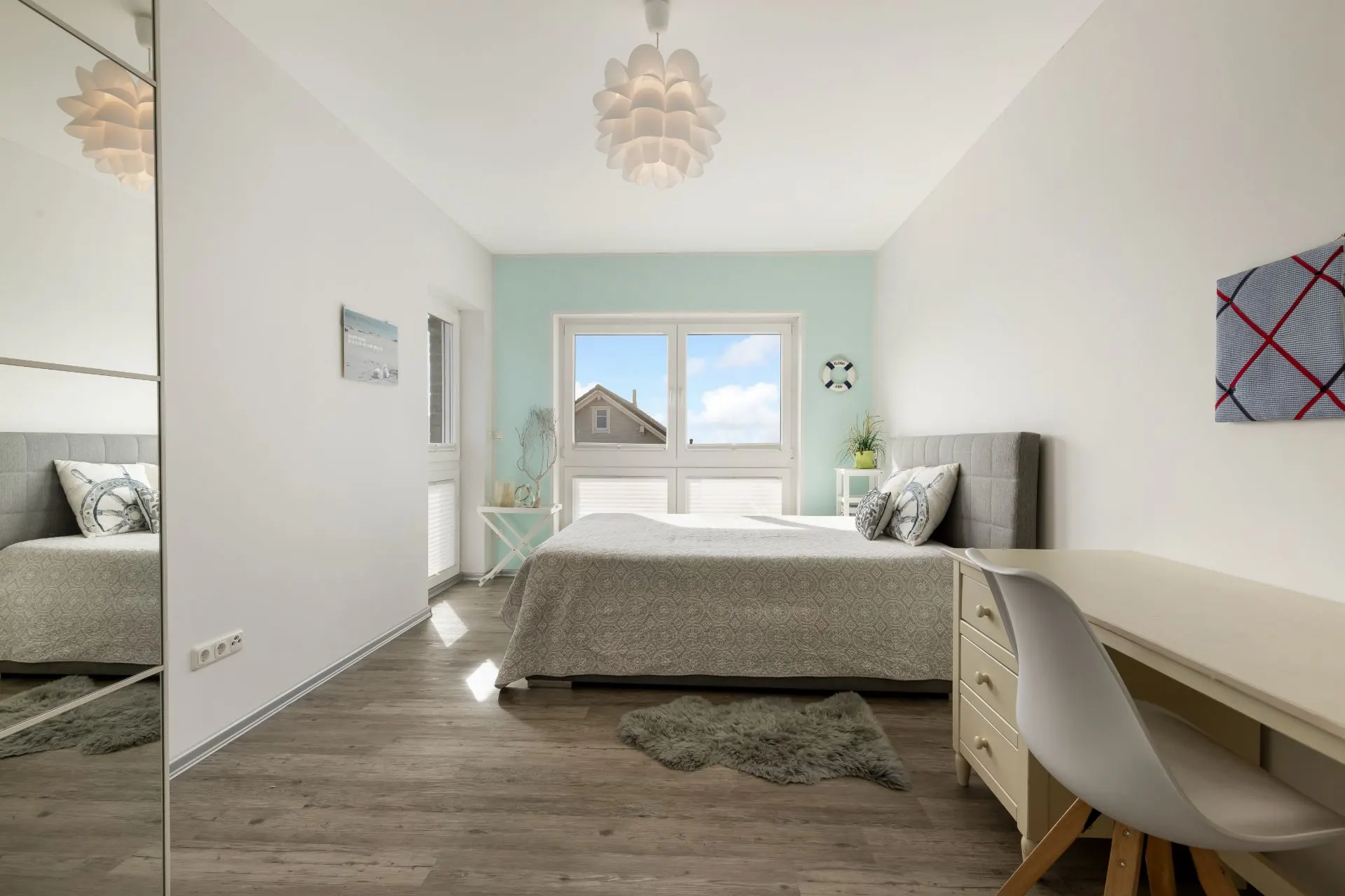 Helles Schlafzimmer mit großem Bett, Schreibtisch und Fenster mit Blick nach draußen.