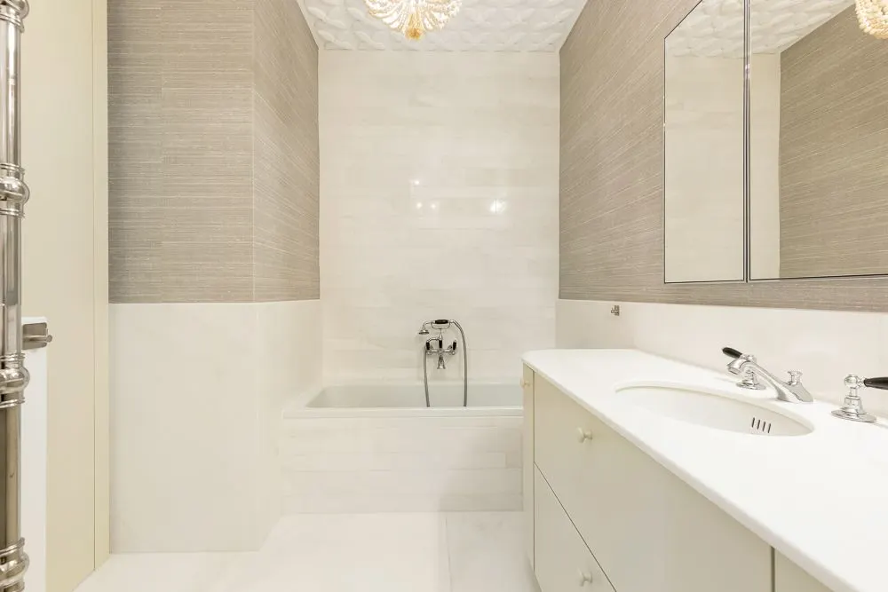 Modernes Badezimmer mit Badewanne, Waschtisch mit Waschbecken und großem Spiegel.